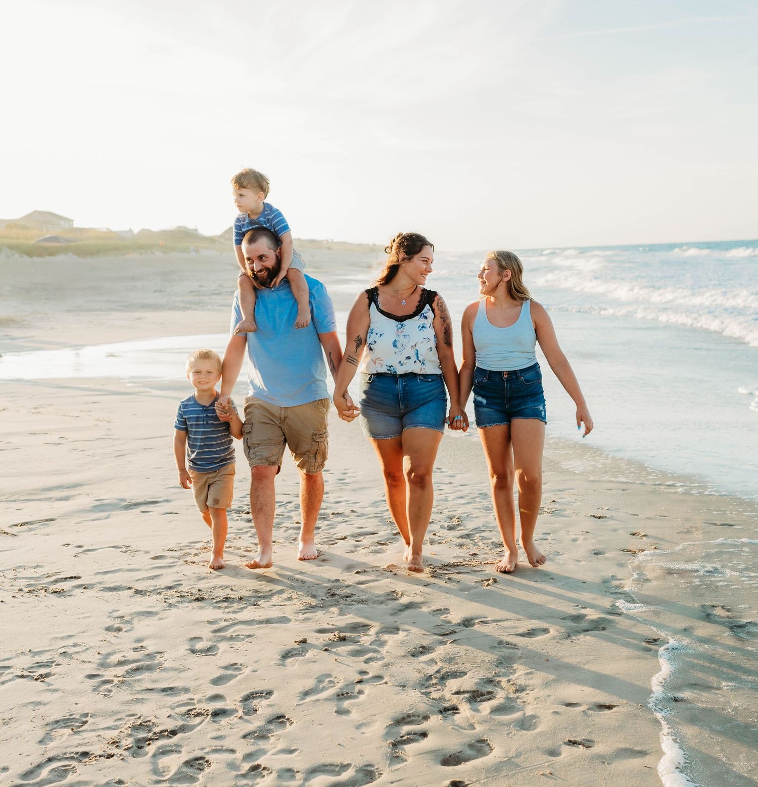 Group walking together along a sunny beach shoreline.