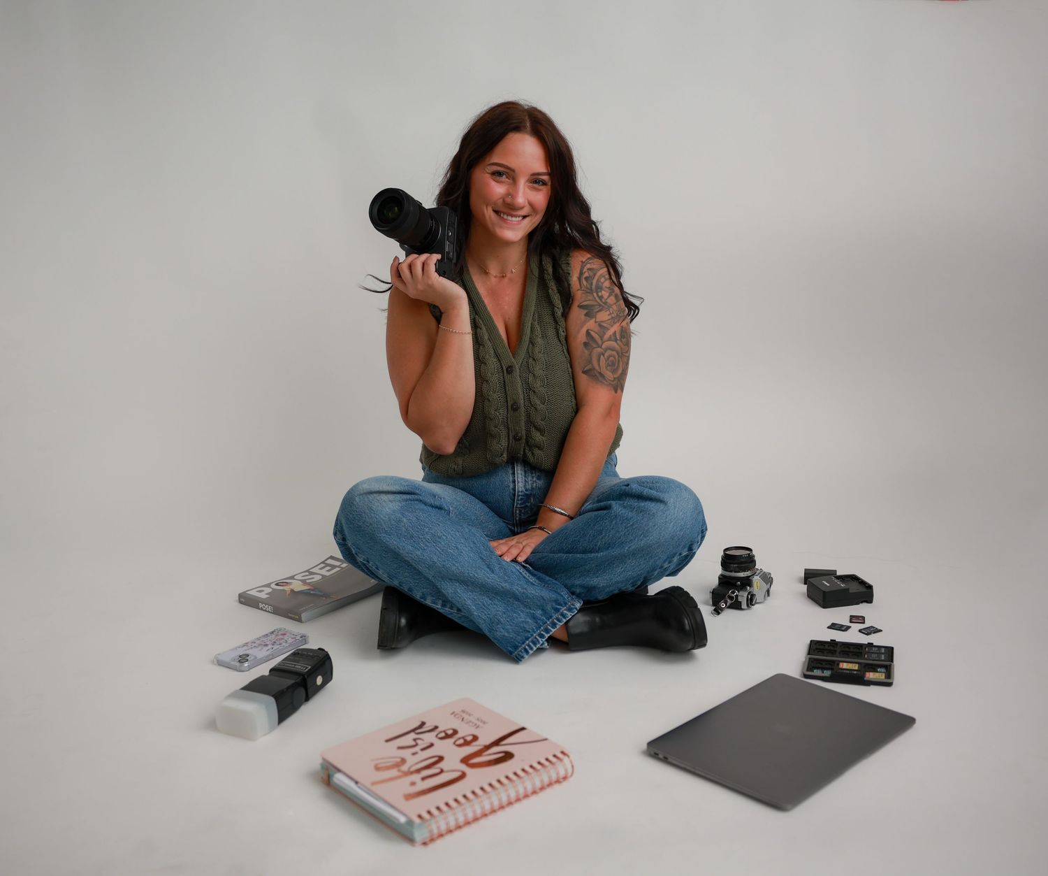 Photographer's lifestyle branding session with laptop and camera equipment on light background.