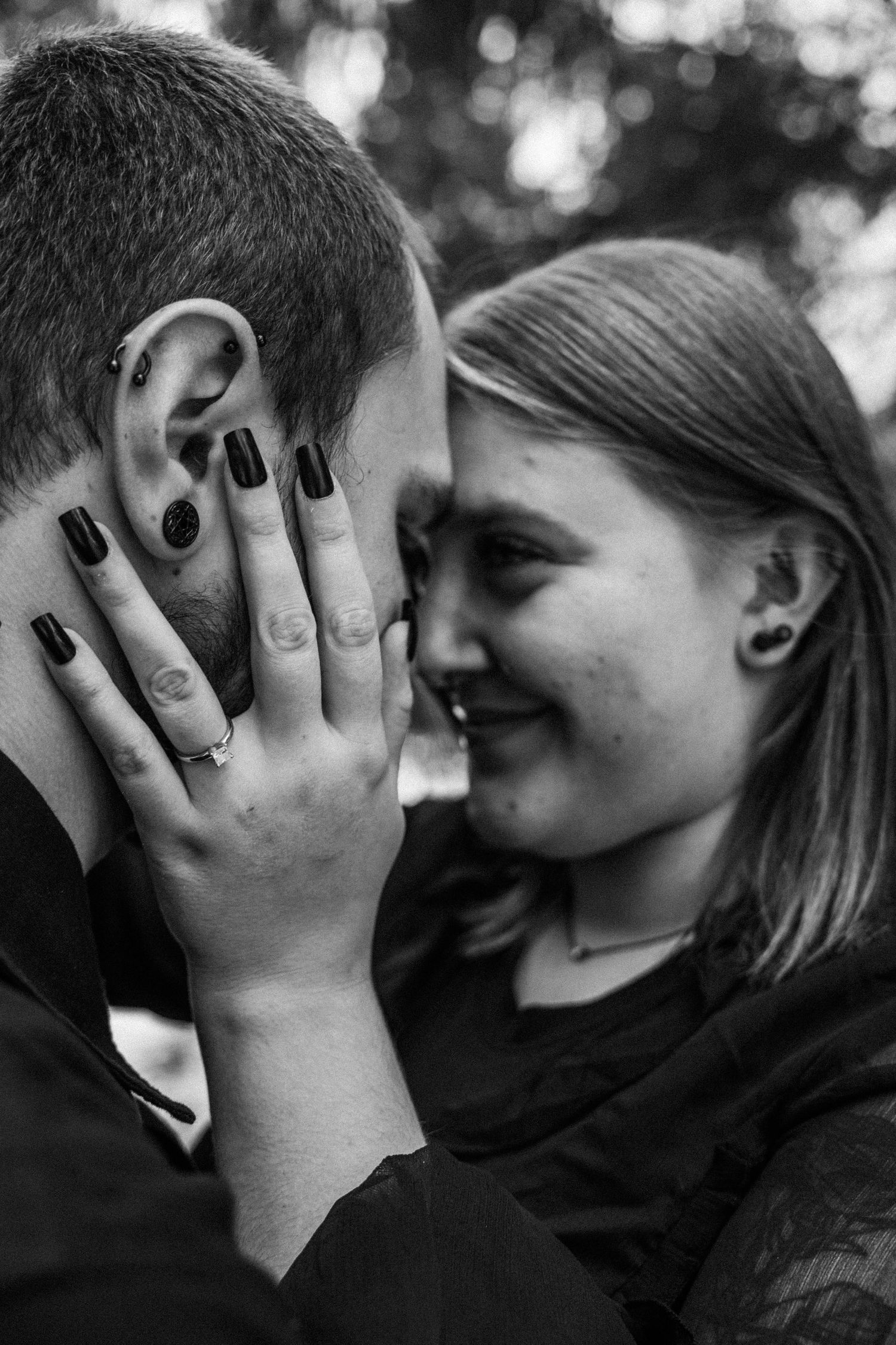 Black and white intimate portrait showing a tender moment between a couple, with the most beautiful engagement ring as the focus.