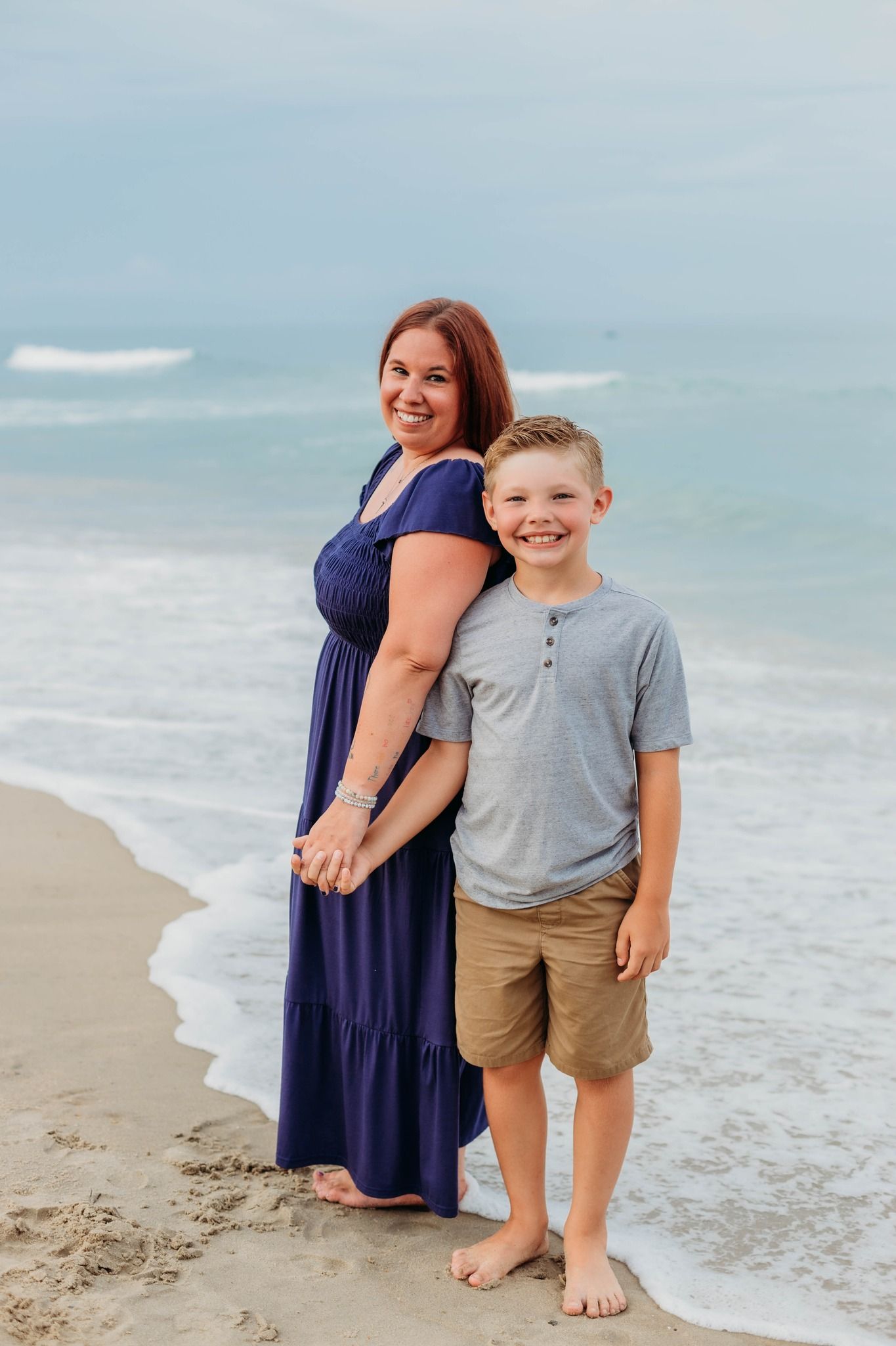 Beachside scene with ocean waves and sandy shore on a cloudy day.