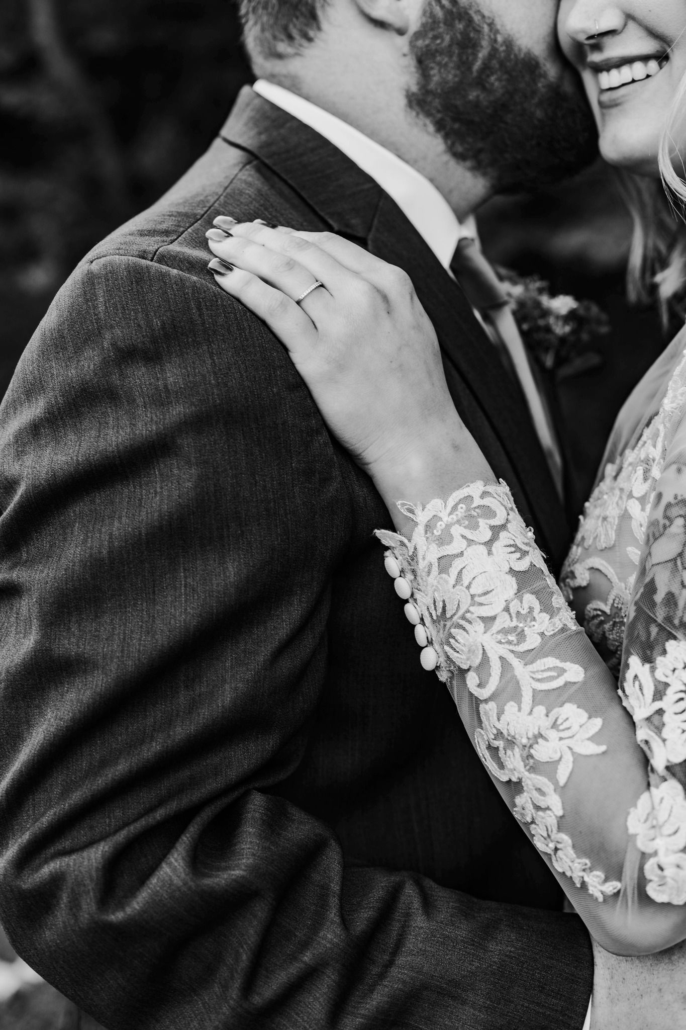 Black and white wedding detail shot showing lace sleeve and engagement ring.