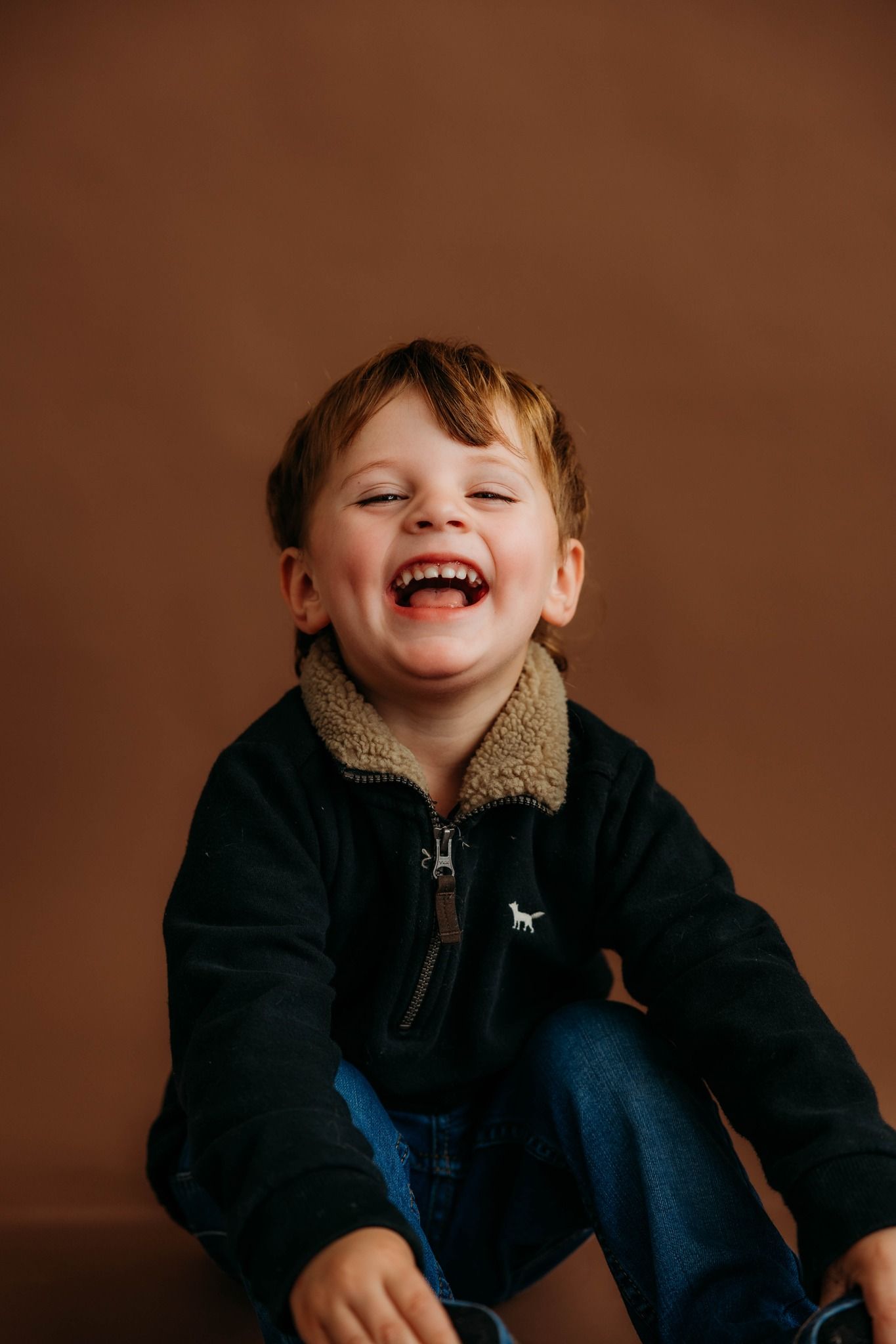 All smiles for this 2 year old located in studio with a beautiful cocoa backdrop.