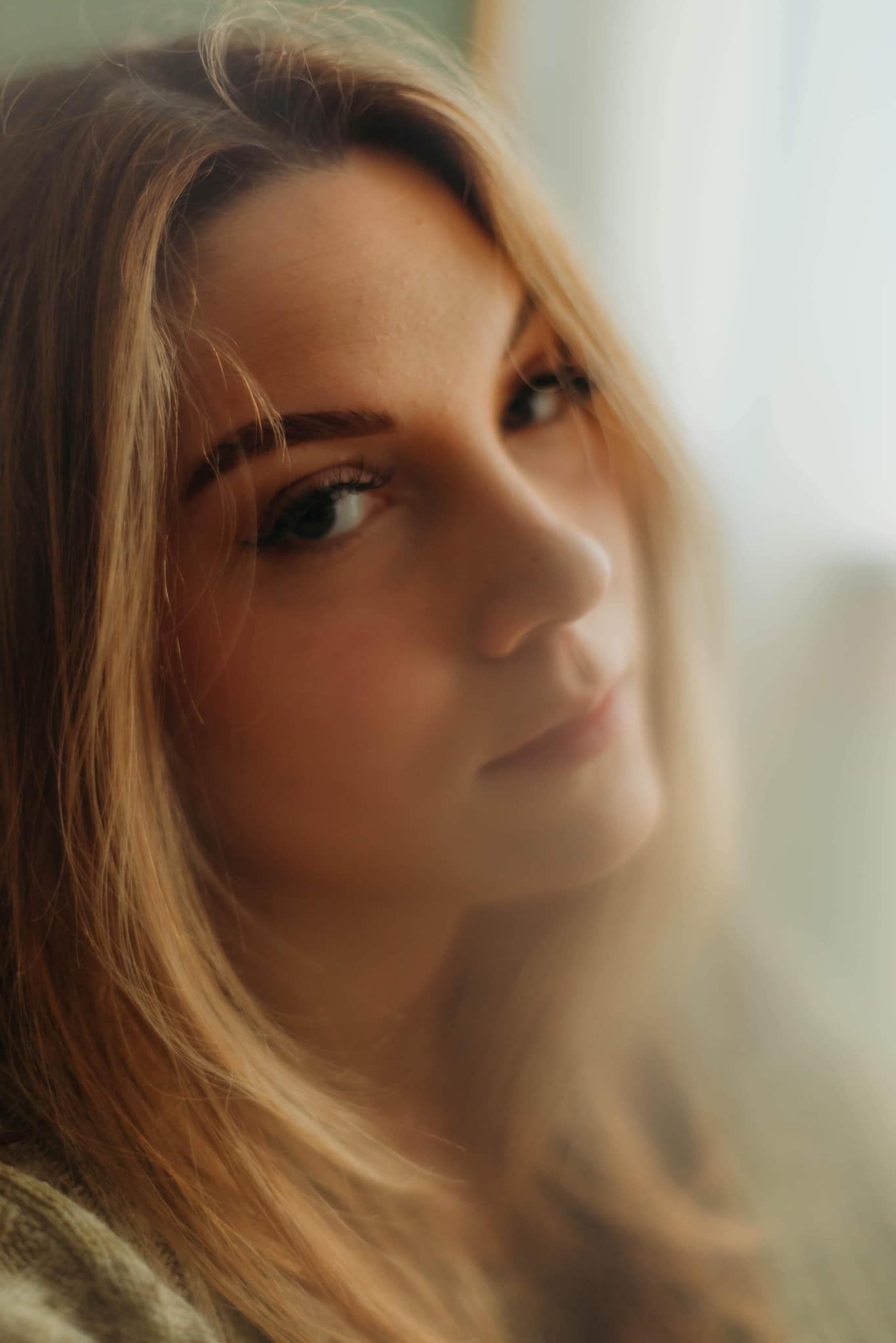 Dreamy close-up portrait with soft natural window lighting and warm tones.