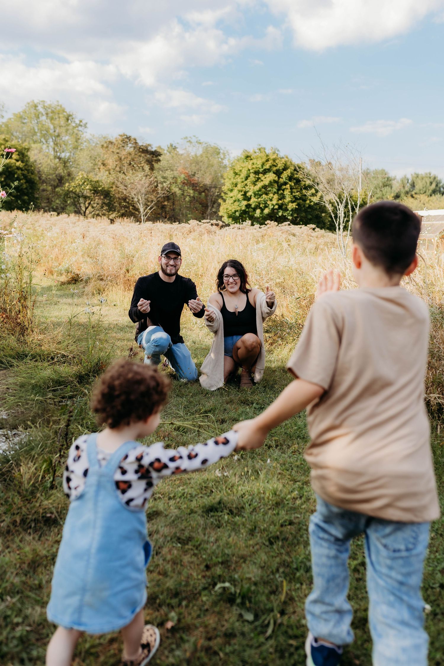 Natural family photography session in field with golden sunlight and casual poses.