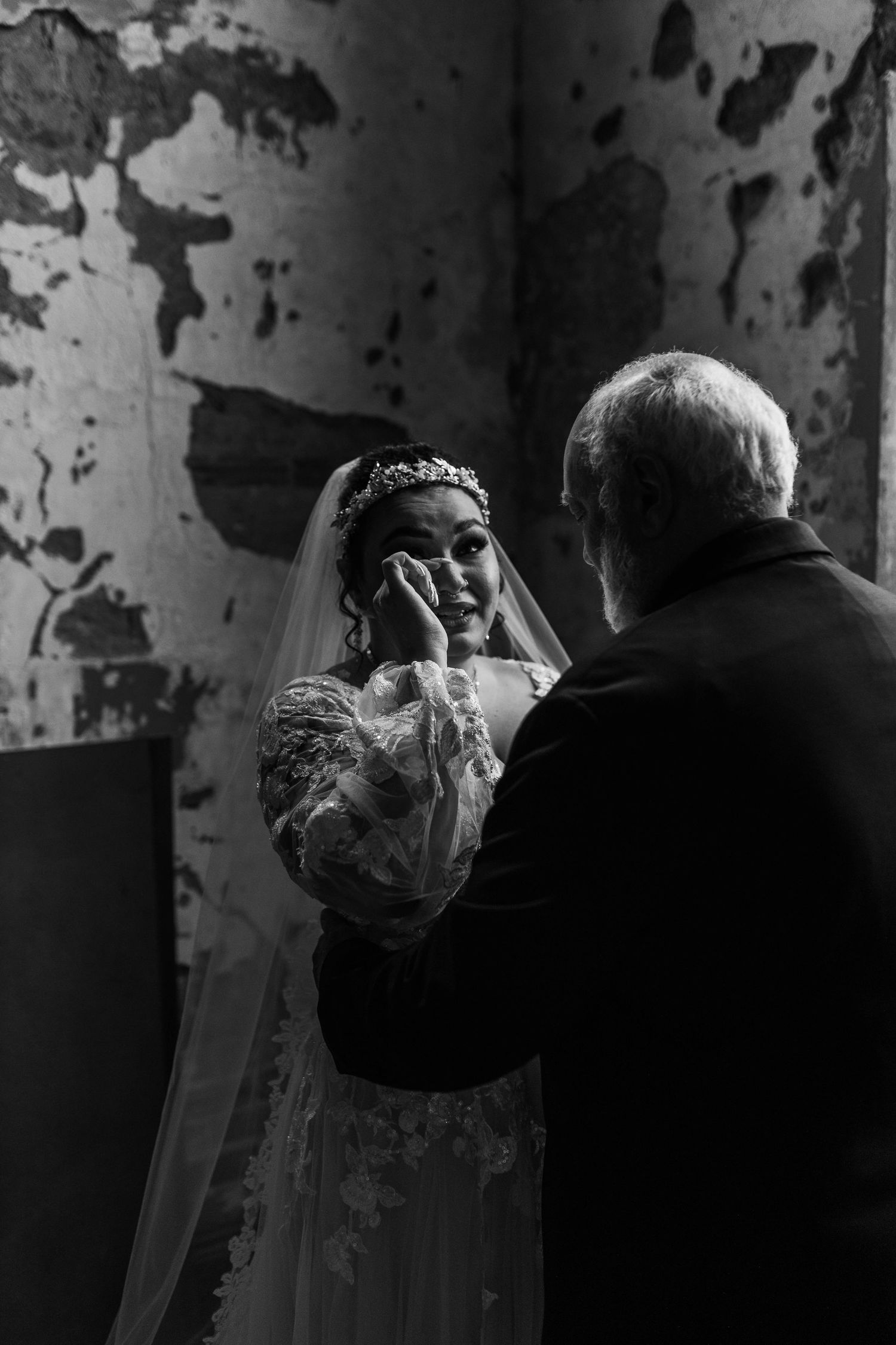 Atmospheric black and white wedding photos taken in a room with peeling walls.