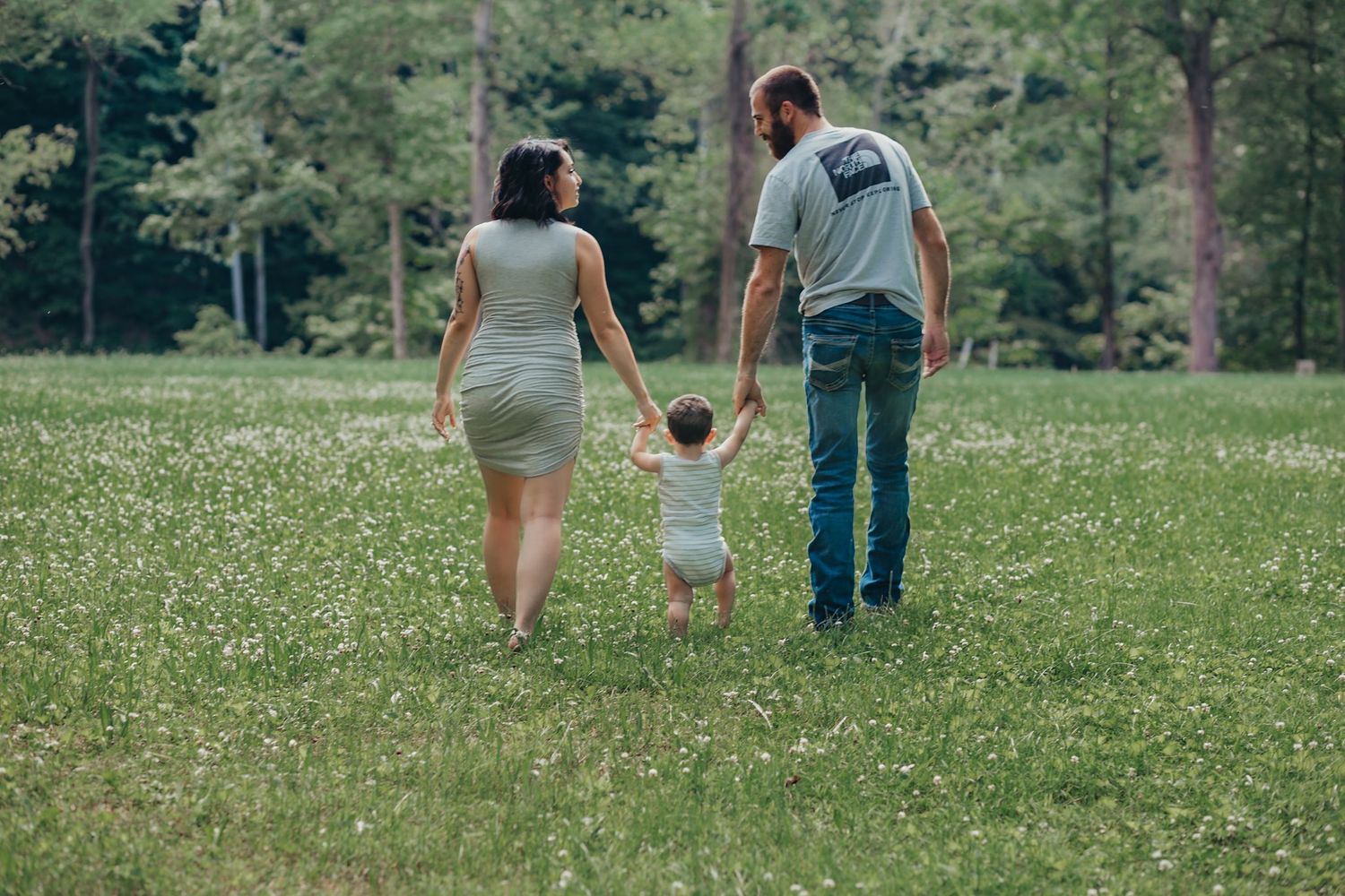 Family walking together holding hands in a green summer meadow.