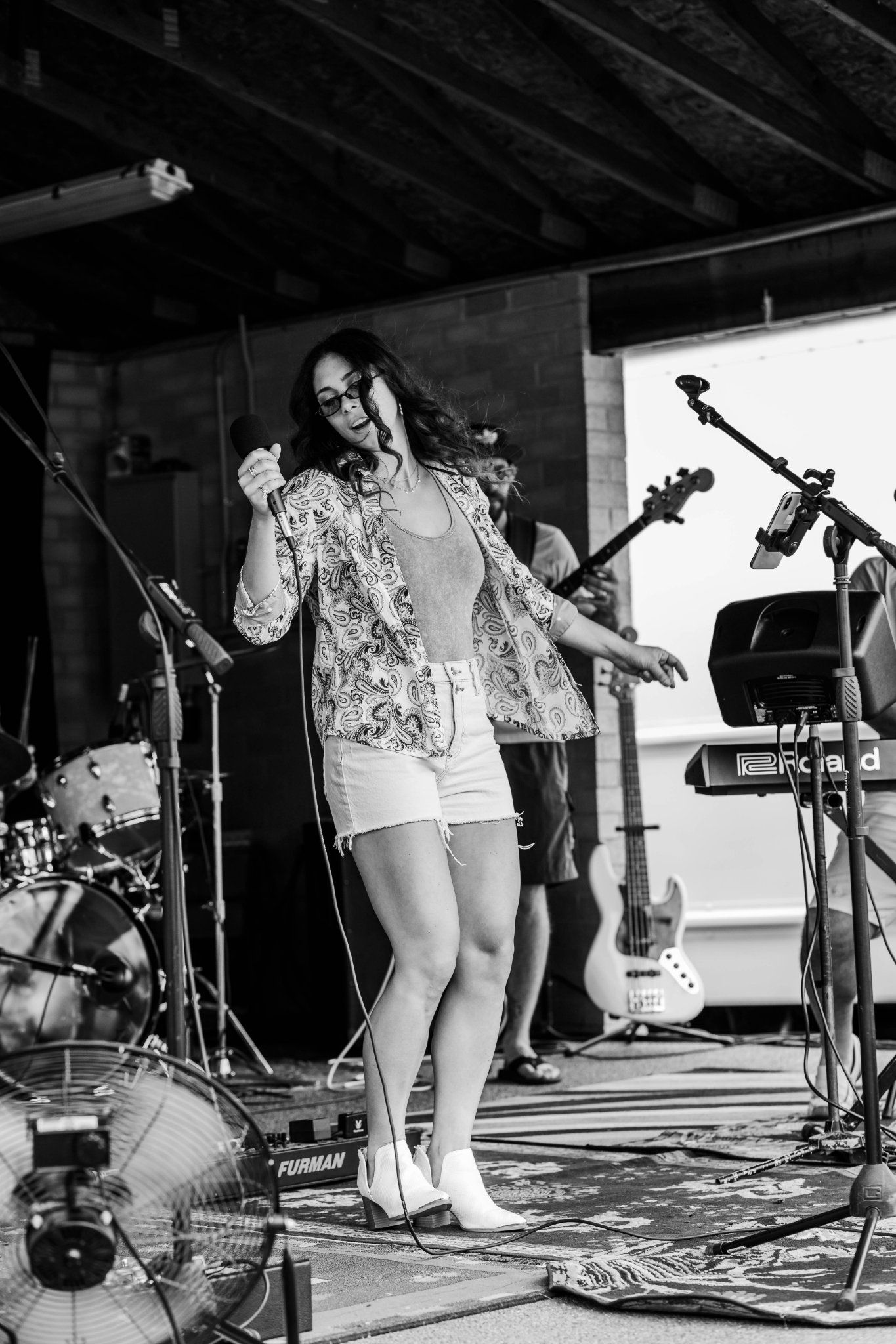 Performer singing on stage with musical equipment in black and white photography.