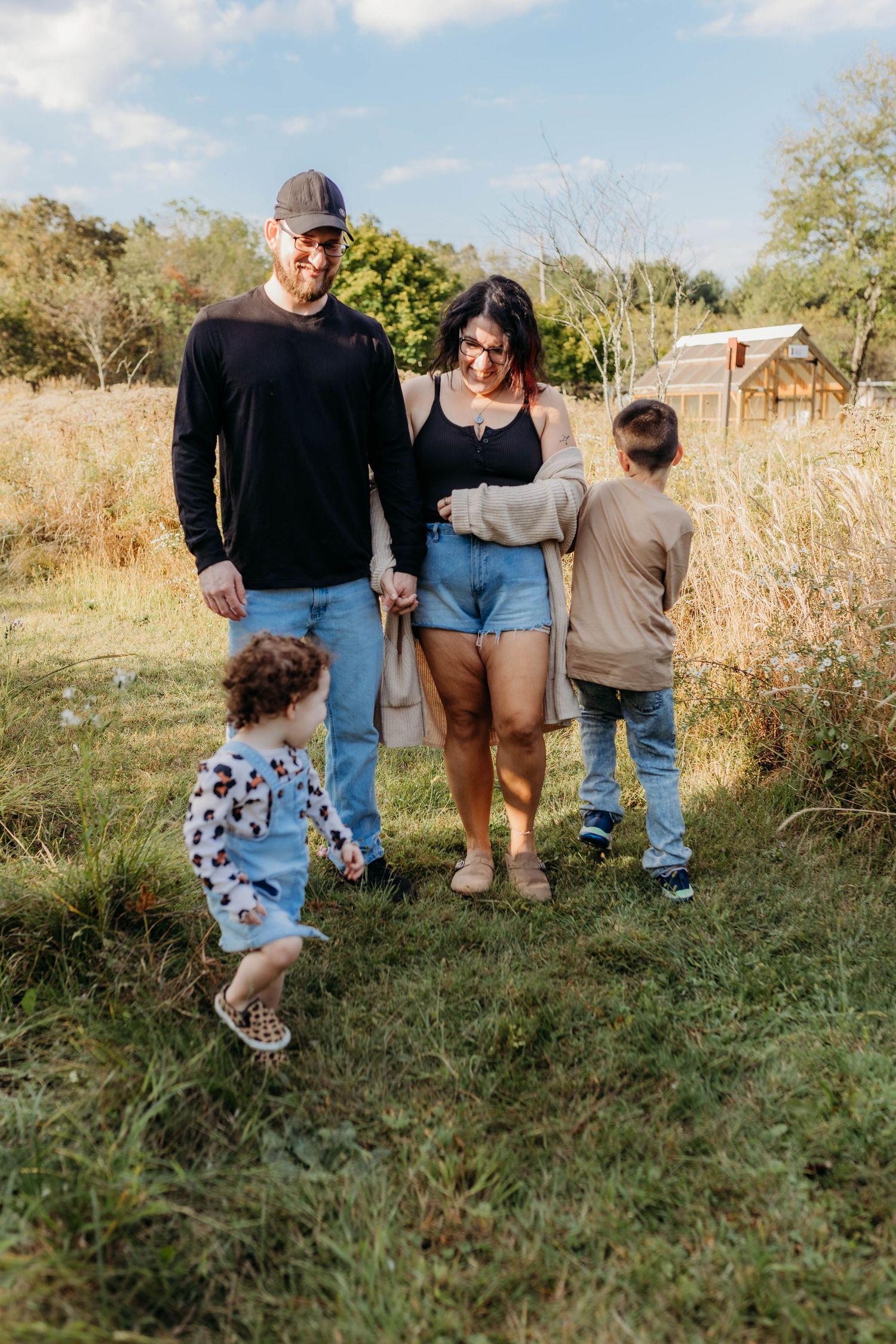 Three people walking together through the grassy field at crooked creek on a sunny autumn day.