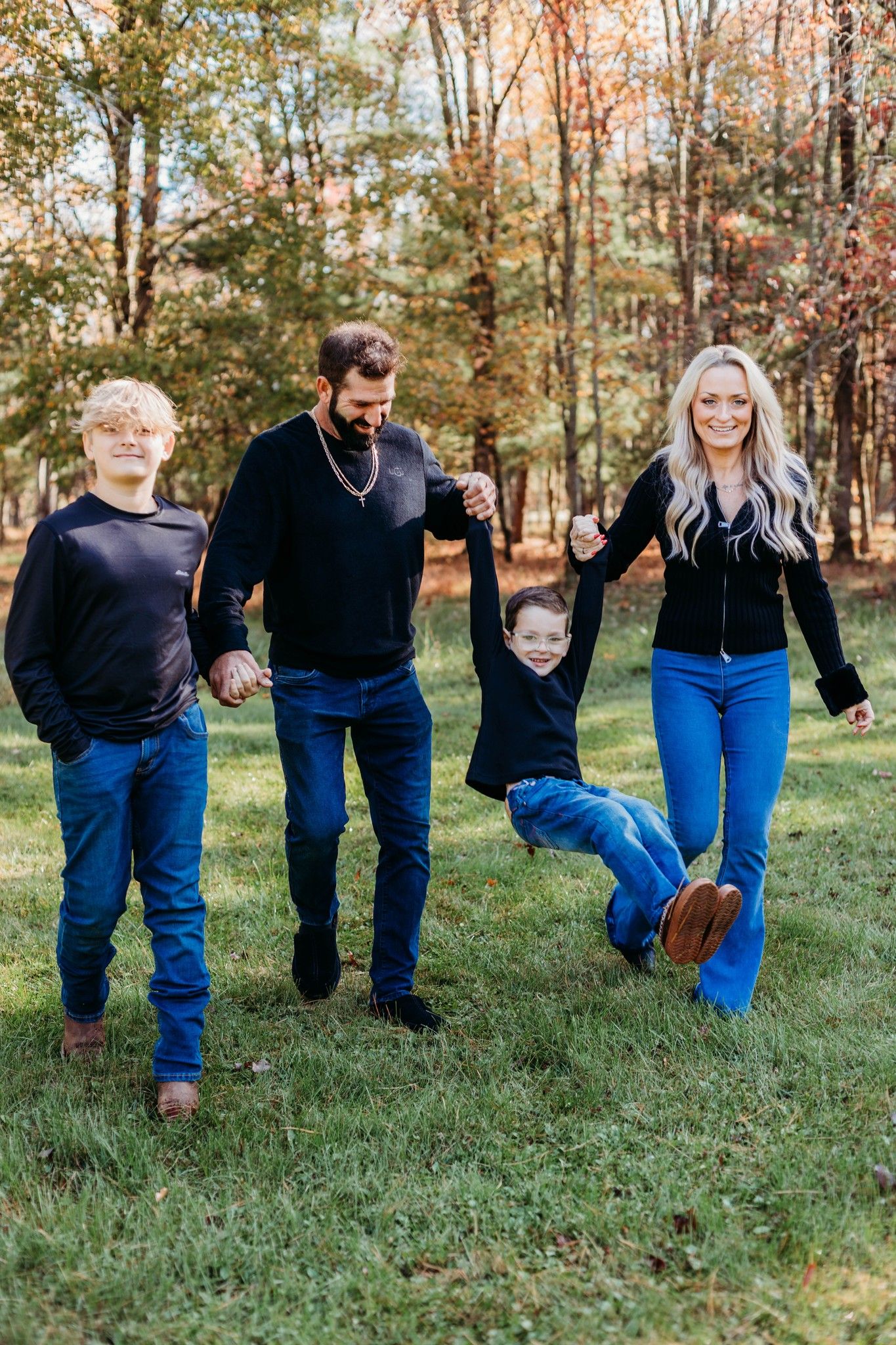 Family wearing matching navy blue outfits walking through autumn trees in a creative photo sequence.