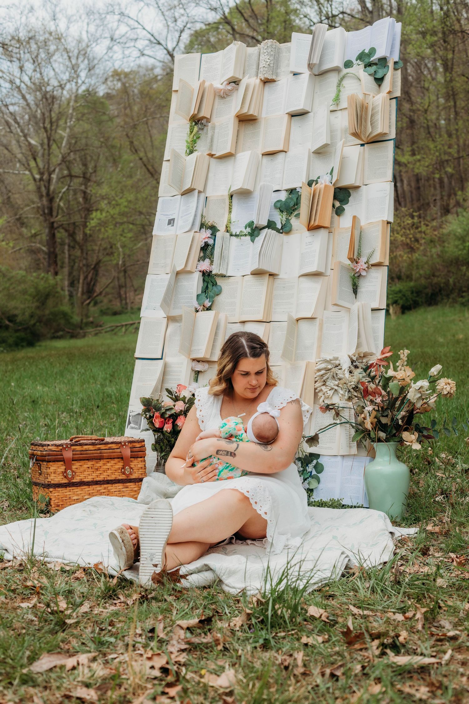 Maternity photoshoot with vintage books backdrop and floral accents in outdoor garden setting.