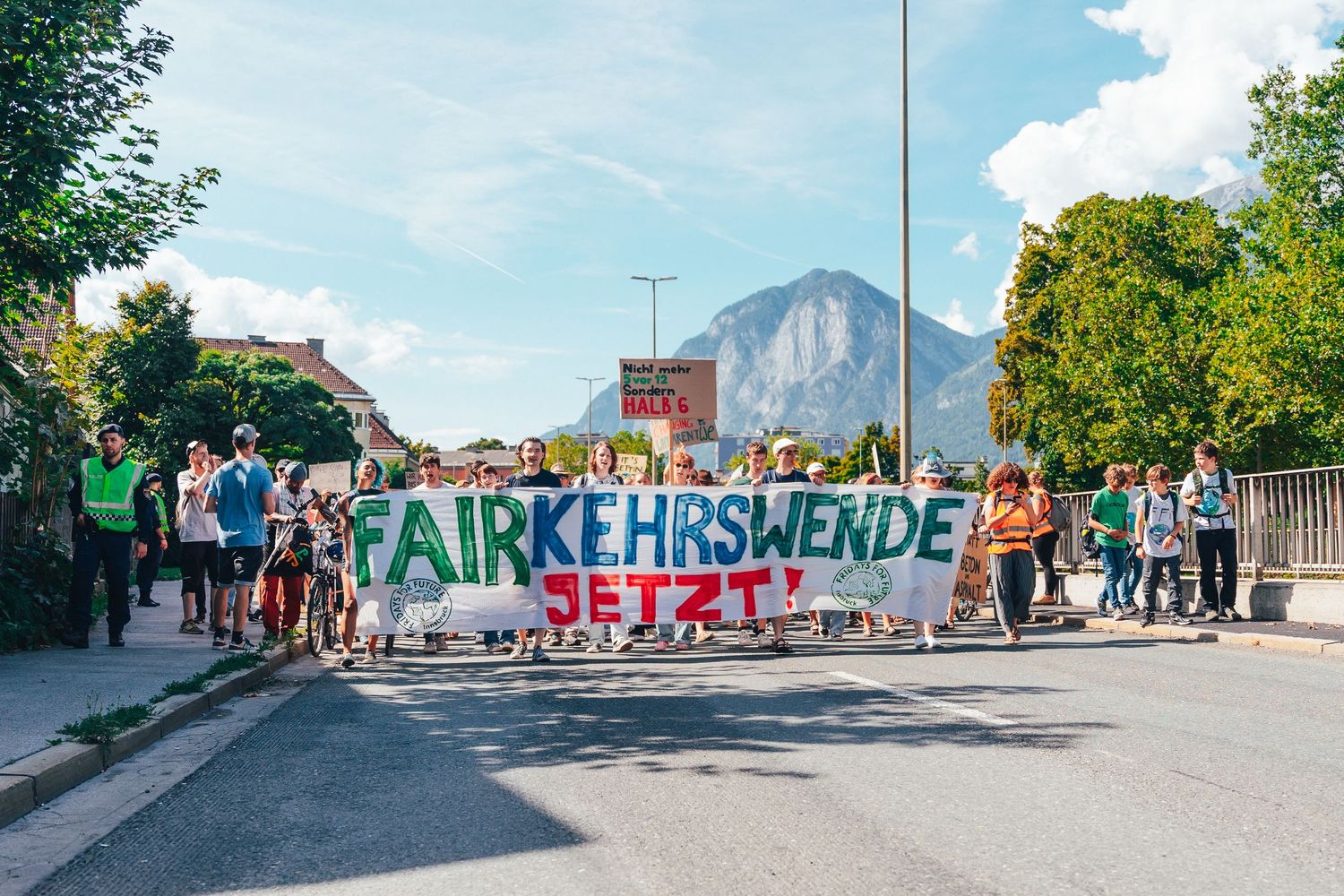 Protest scene at Innsbruck. A group of demonstrators holding signs with messages about Climate Change.