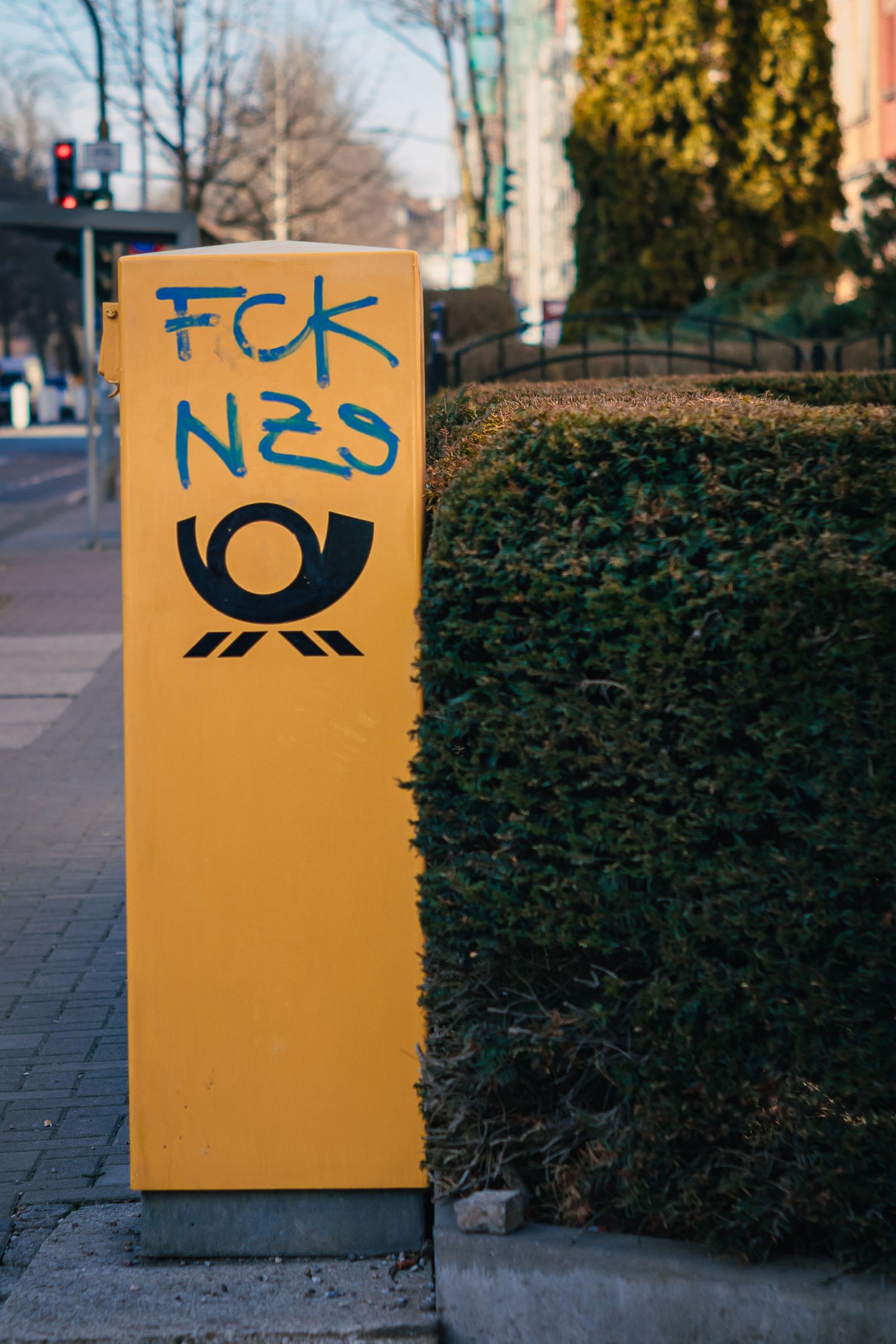 A yellow mailbox with a graffiti on it.