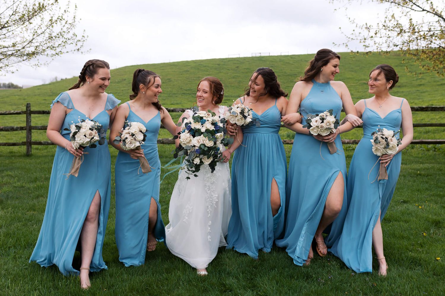 bride walking in the middle of her bridesmaids while linked arms and smiling at each other