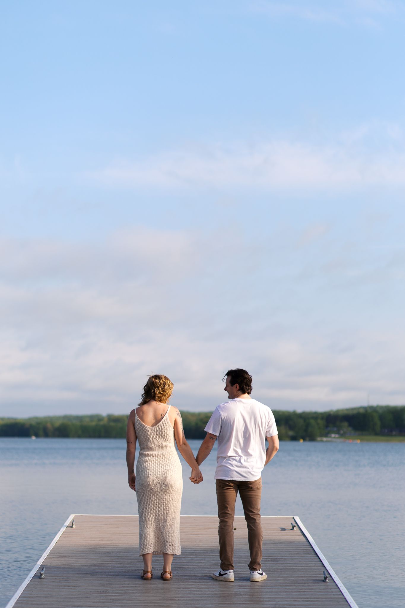 couple holding hands with their back to the camera standing on a dock at Moraine State Park