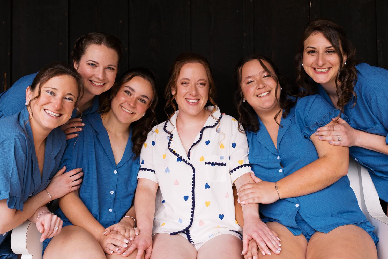 bride sitting with her bridesmaids smiling at the camera