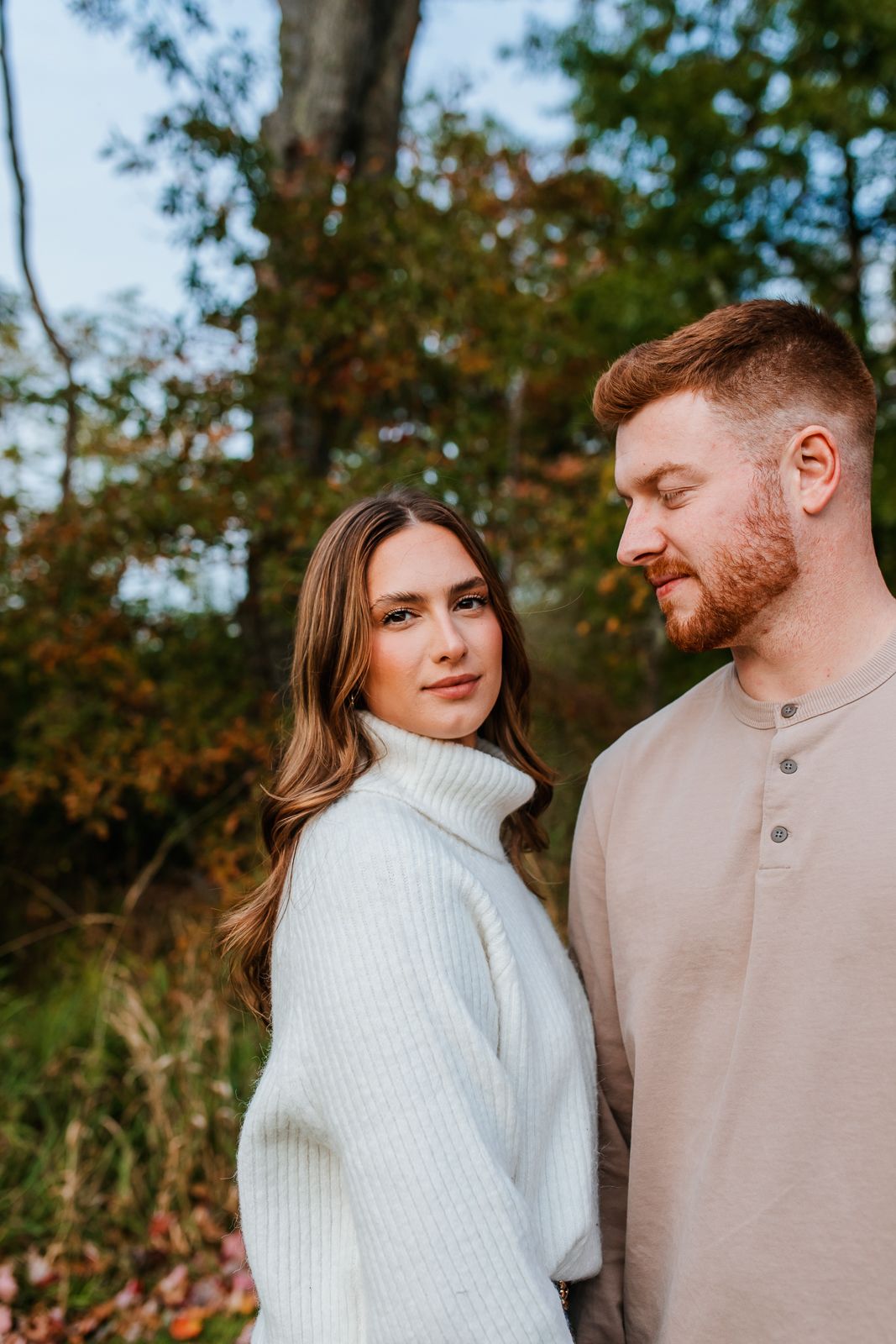 beautiful woman looking at the camera during engagement session while her fiance looks at her