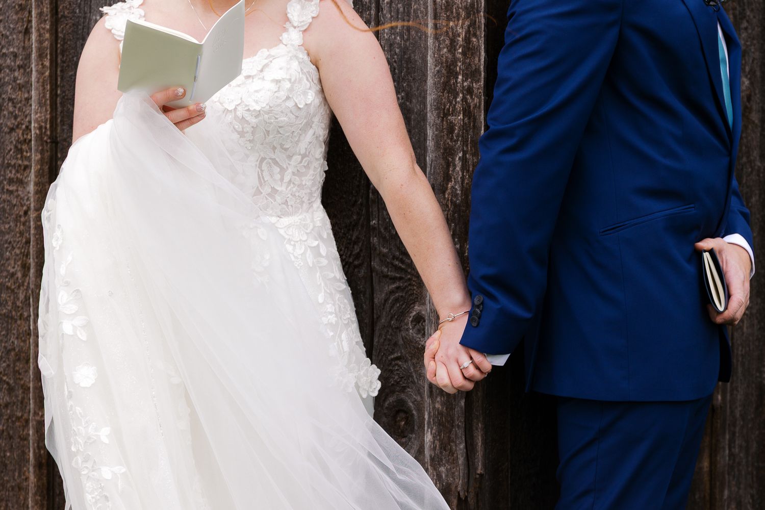 close up of bride and groom holding hands around a corner during their first look and private vow reading