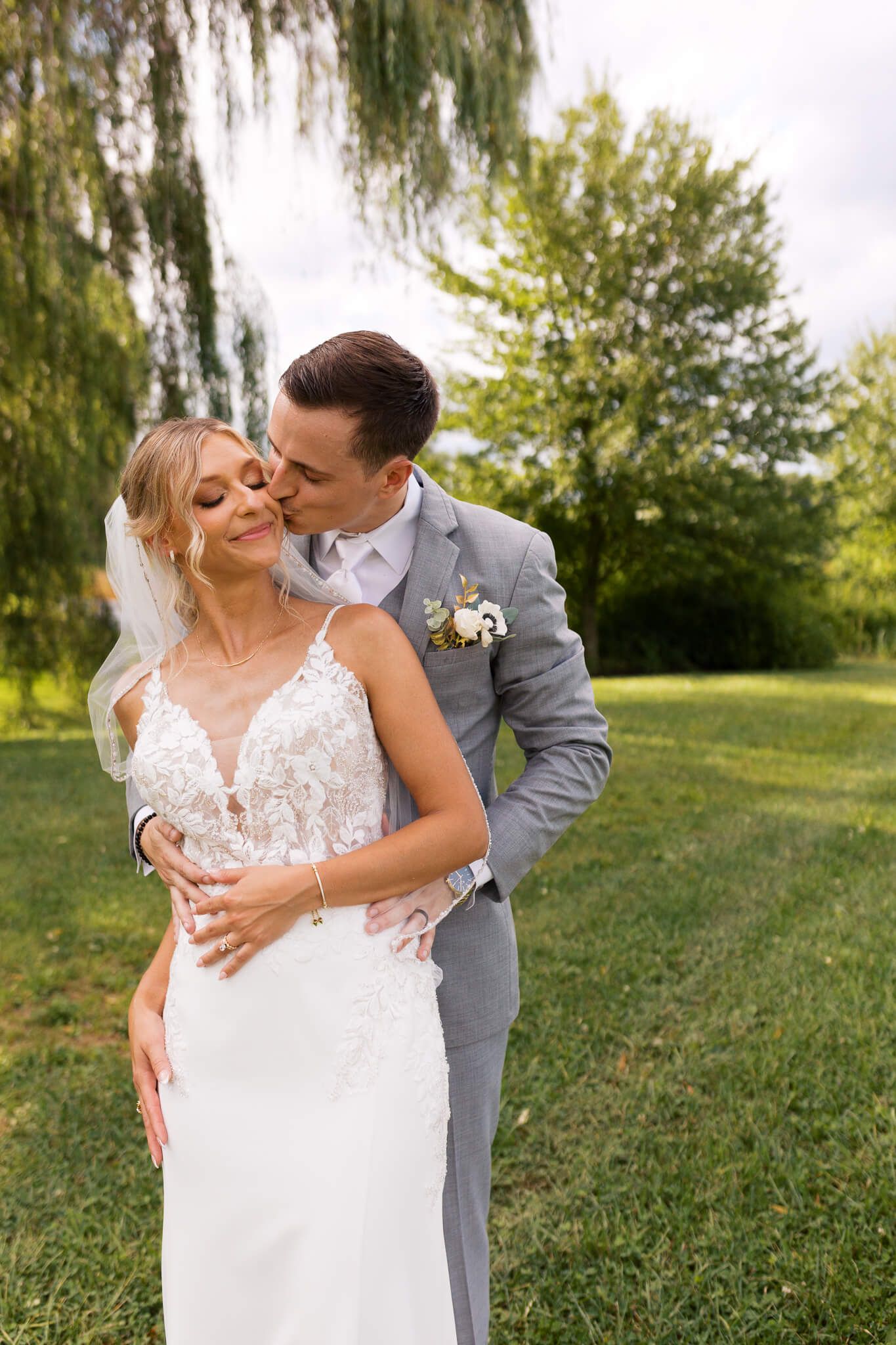 Groom kissing bride on the cheek playfully during bridal portraits at Willowbrook