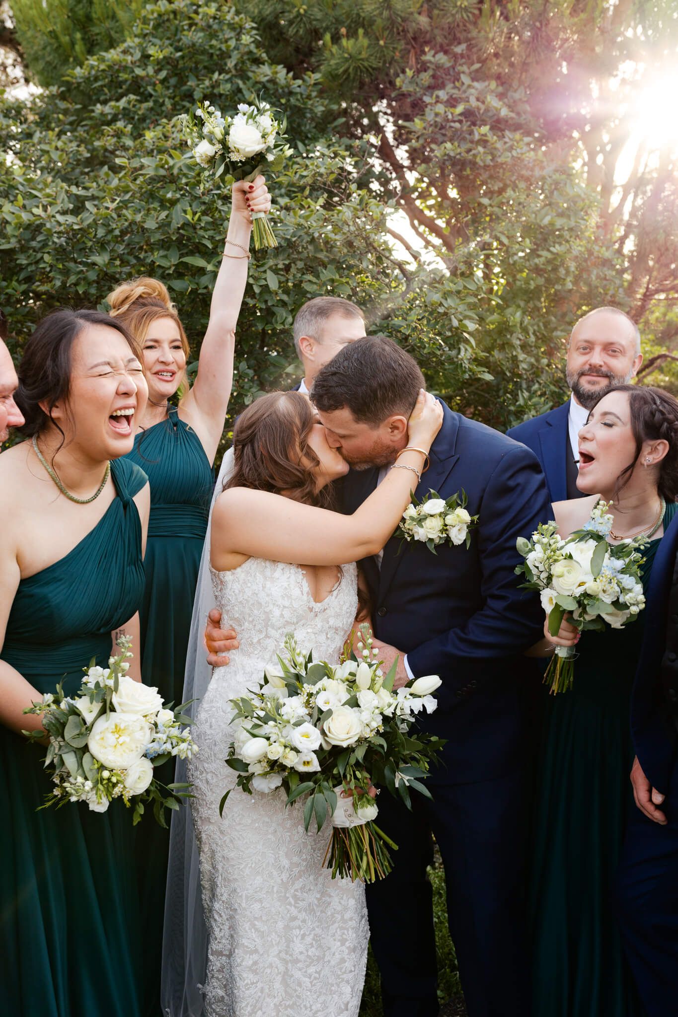 Couple shares a kiss as their bridal party joyfully cheers them on