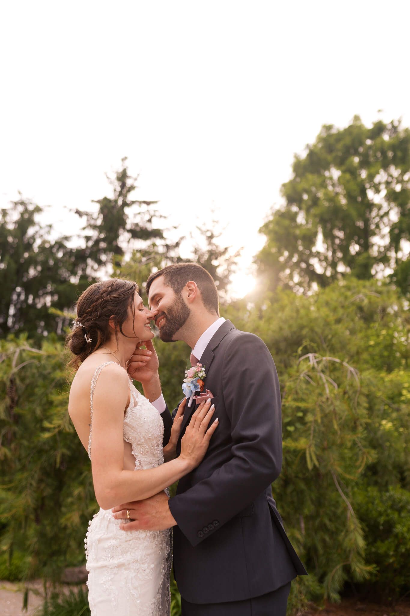 bride and groom smiling while going in for a kiss with the sunlight behind them