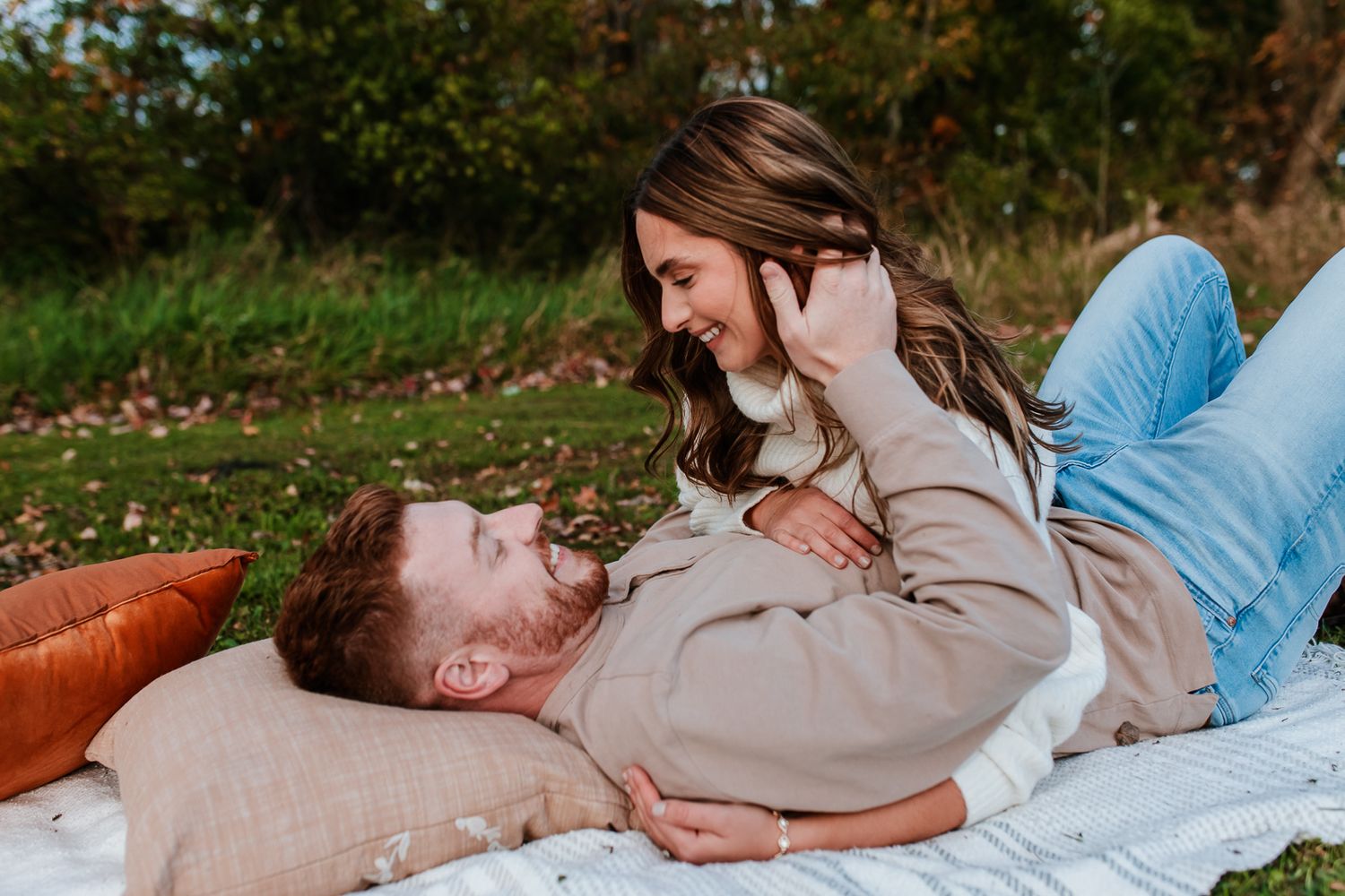brunette woman looking down at fiance as they share a laugh on a blanket