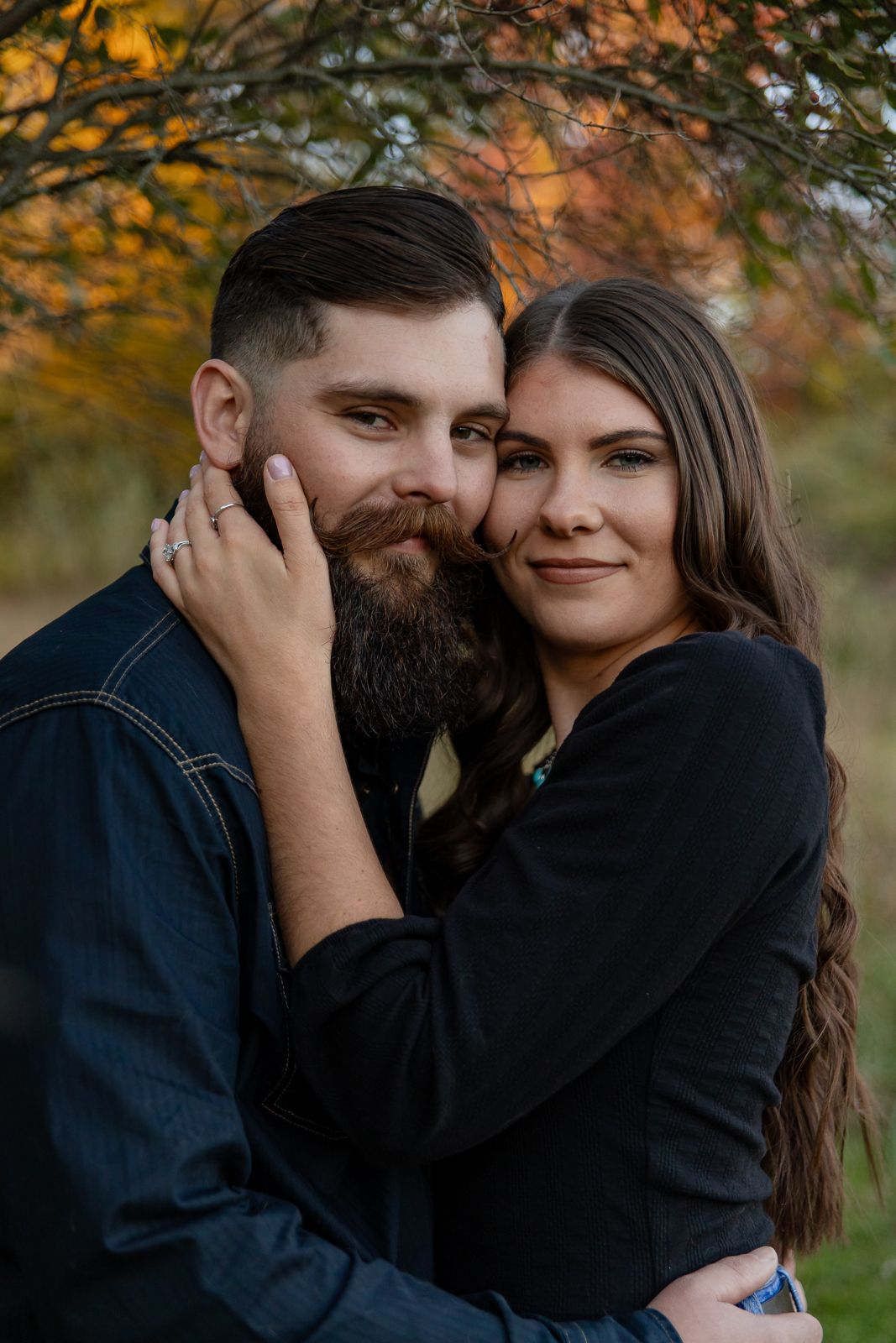 beautiful woman and handsome man with handlebar mustache looking at the camera during their engagement photos