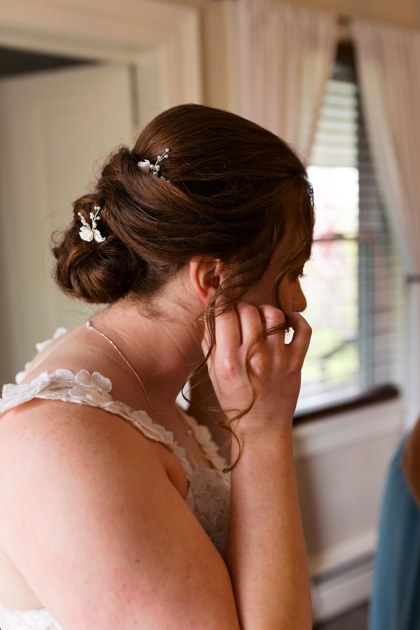 bride putting her earrings on while getting ready for her wedding