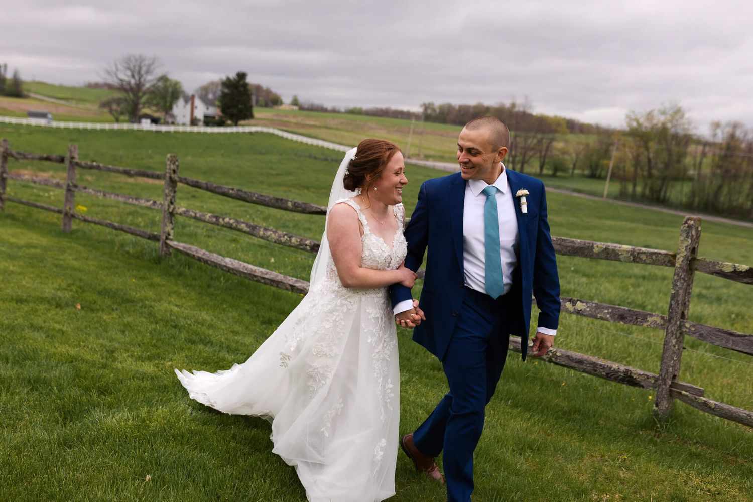 man and woman linked arms walking along fence line
