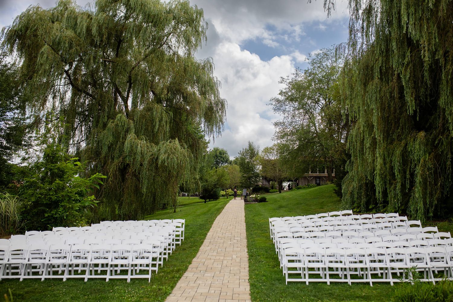 Wedding aisle surrounded by willow trees and perfectly aligned seating for guests