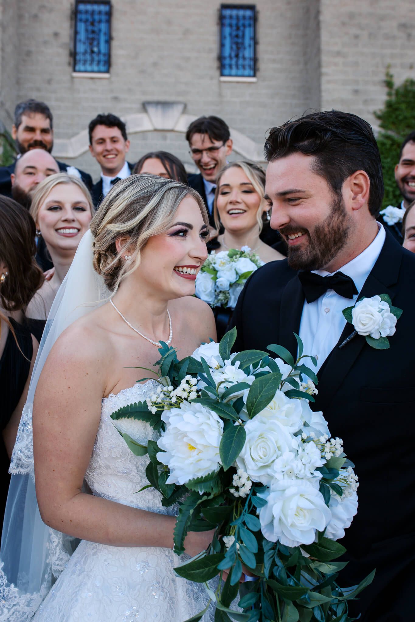 Couple smiling joyfully while surrounded by bridal party while wedding photographer, Emma Craven, captures the moment