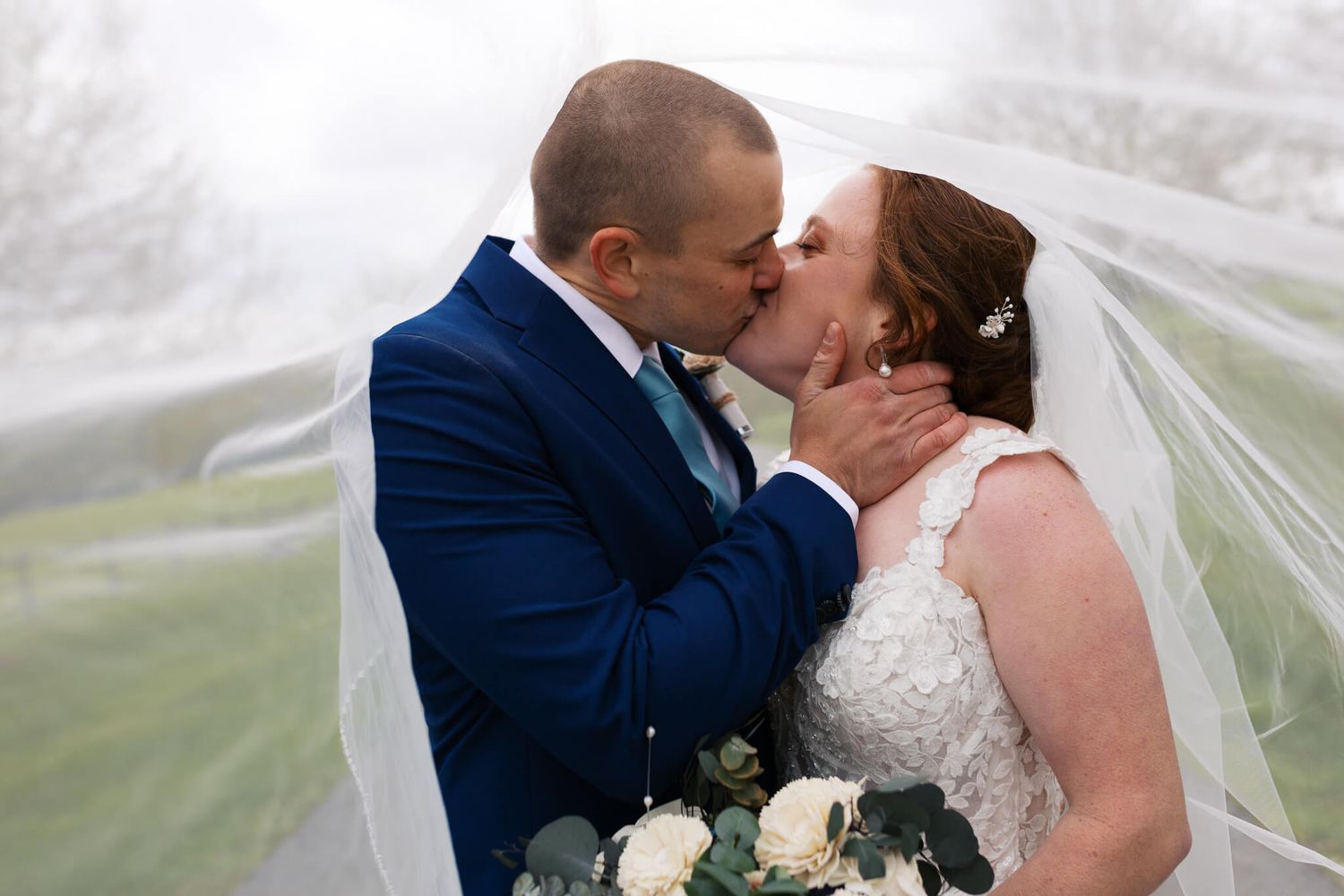 man and woman kissing romantically under veil