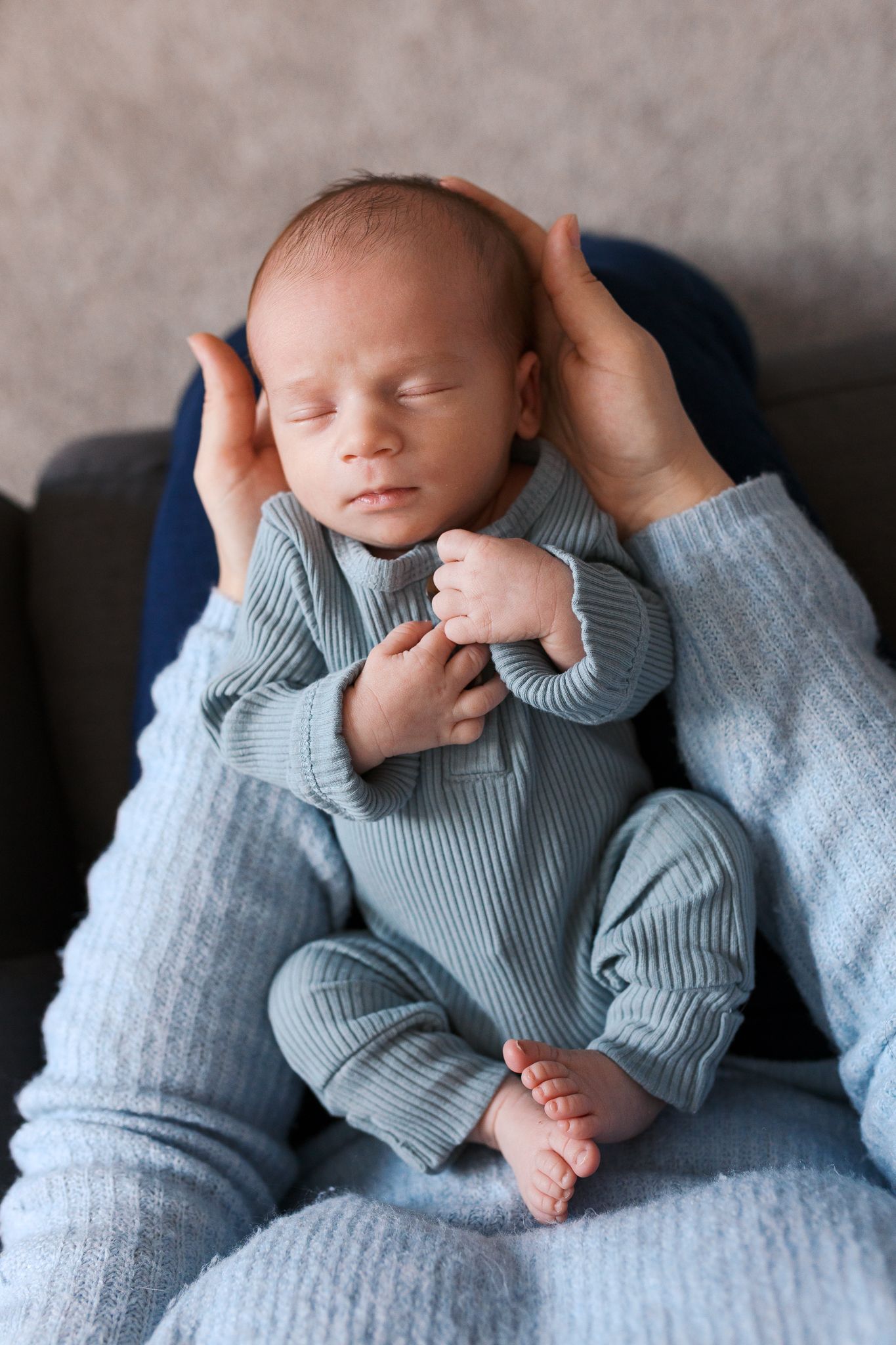baby boy wearing a light blue ribbed outfit laying in the arms of his mom