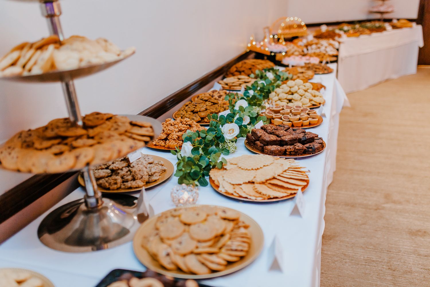 view of a pittsburgh wedding cookie table covered in a white tablecloth with over twenty different types of cookies on plates