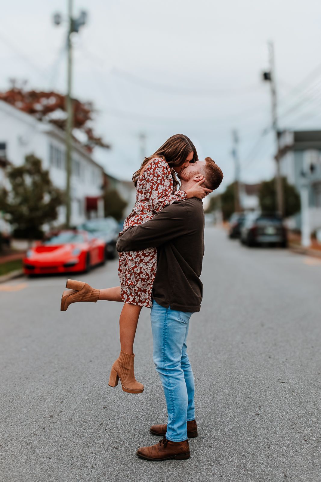 man lifts woman in flower dress and cute boots in the air to give her a kiss in Saxonburg, PA