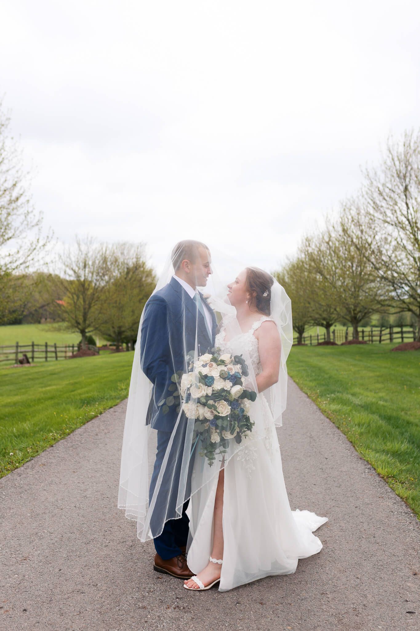 Bride and groom standing under bride's veil smiling at each other at Armstrong Farms in Western Pennsylvania