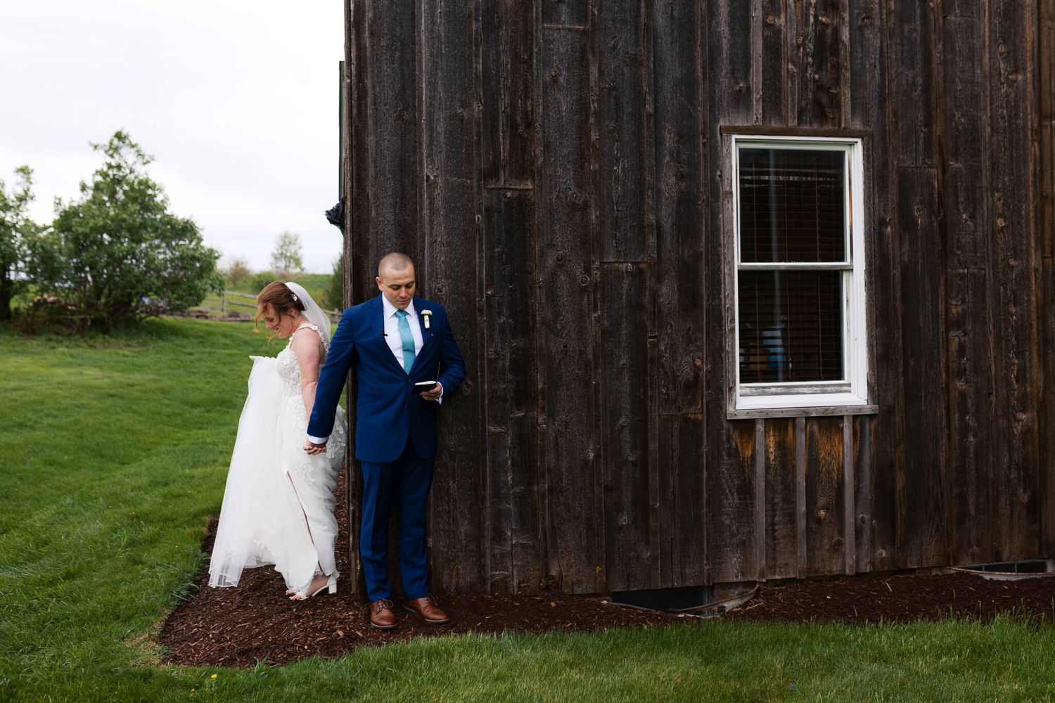 private first touch and vow reading with man and woman holding hands around corner of barn like building at Armstrong Farms