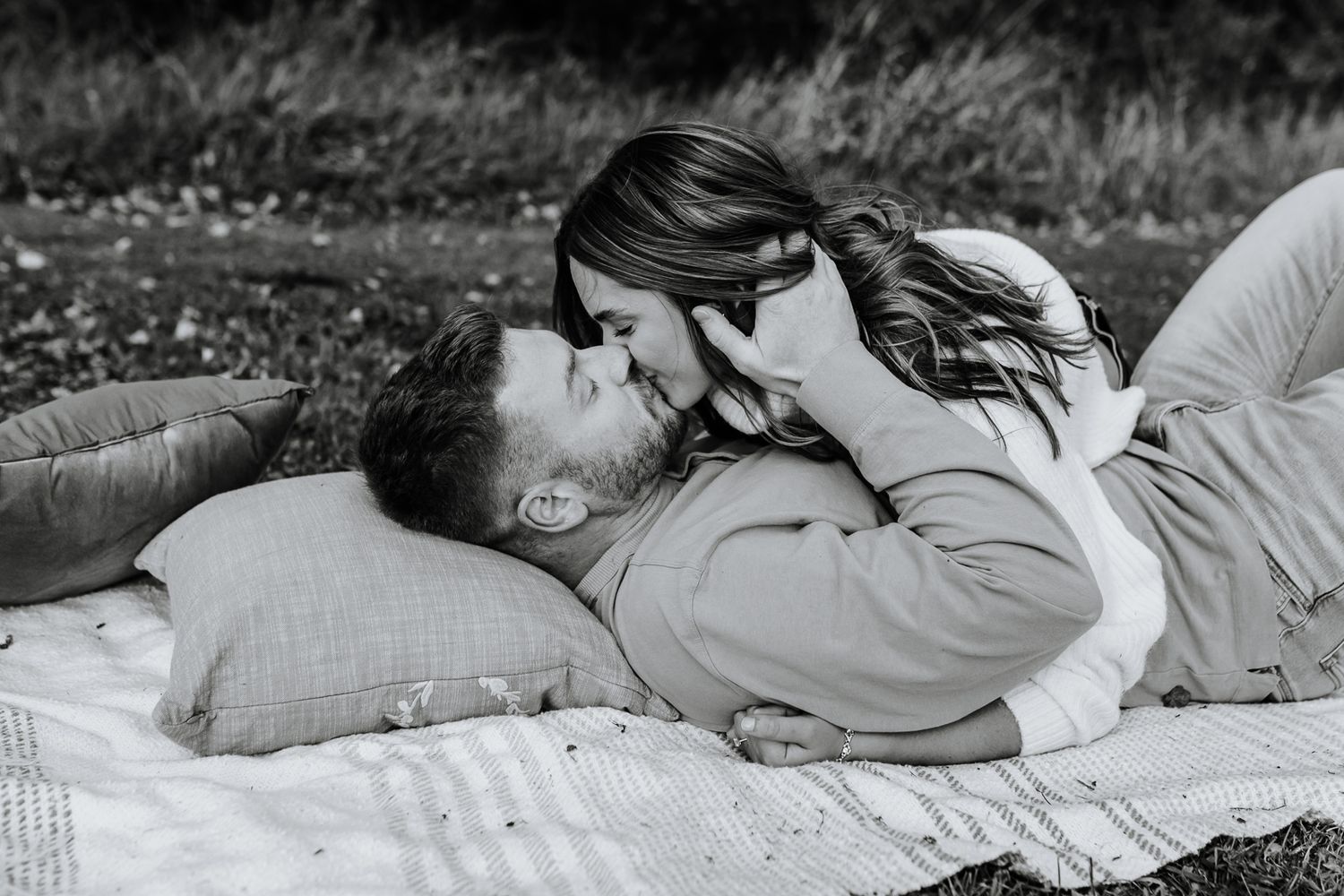 black and white image of a man and woman sharing a kiss during their picnic engagement session