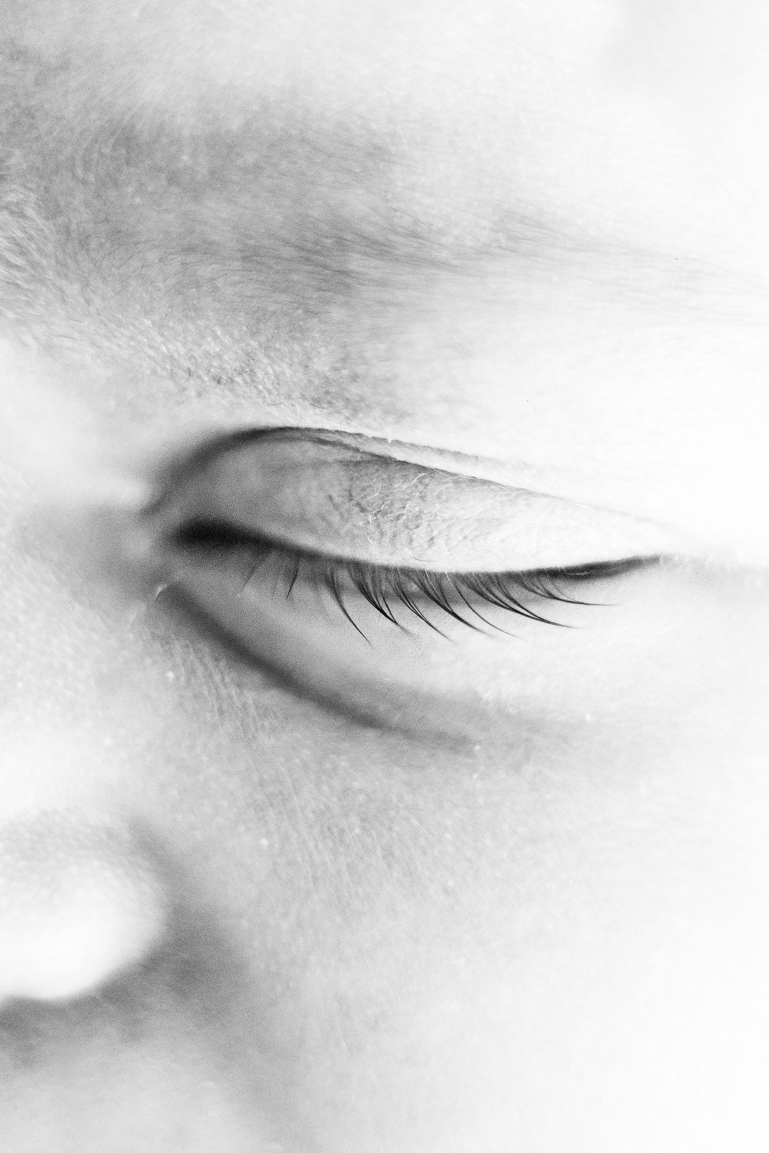 Extreme close-up black and white photo of a sleeping newborns closed eye and long eyelashes.