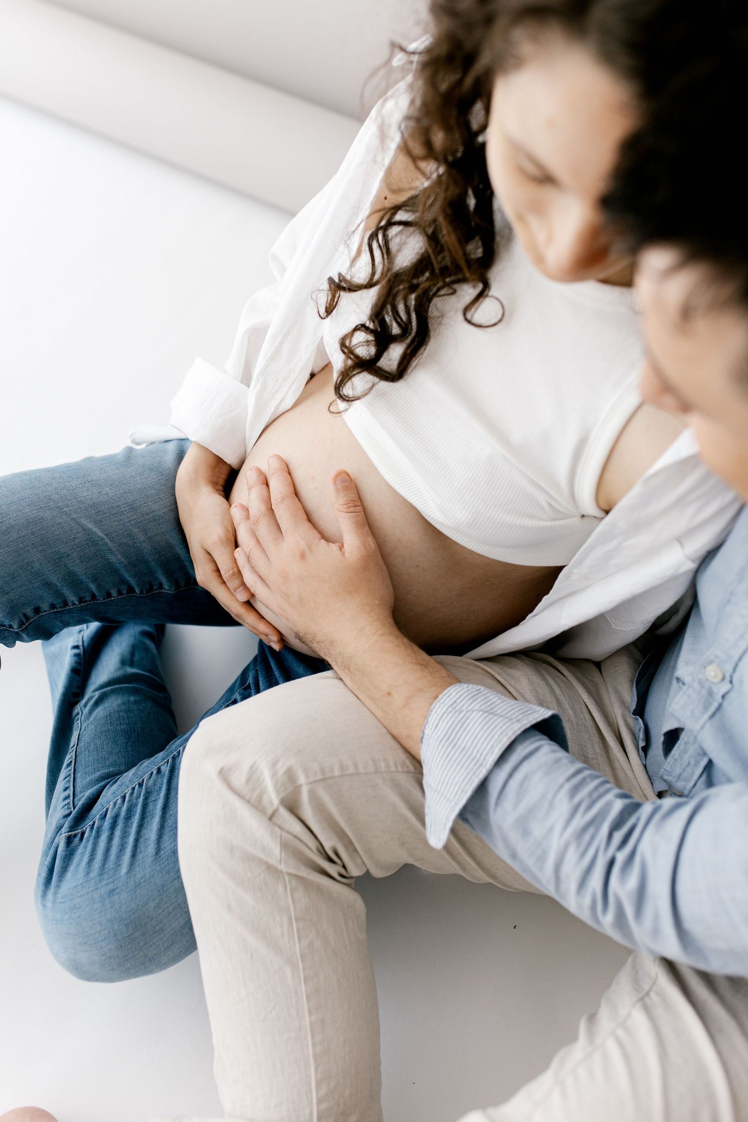 Close-up of couple's hands gently cradling pregnant belly during maternity photo session.