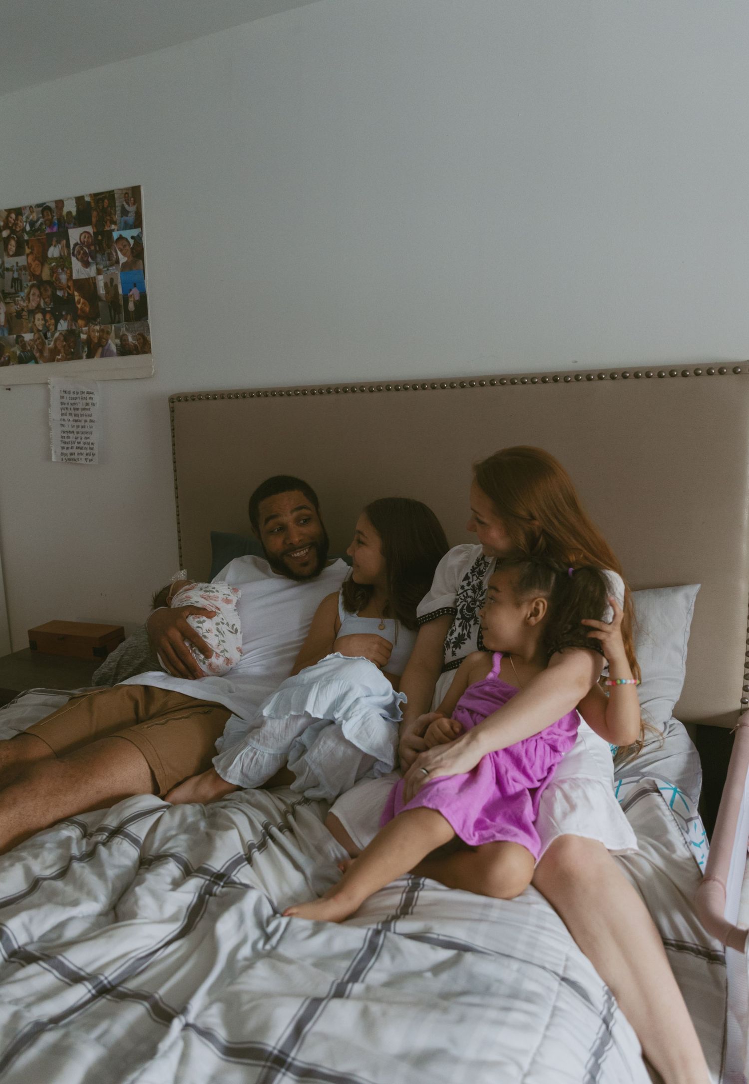 Family snuggling on a bed admiring their newborn baby, during an in-home photoshoot in Sussex, New Jersey