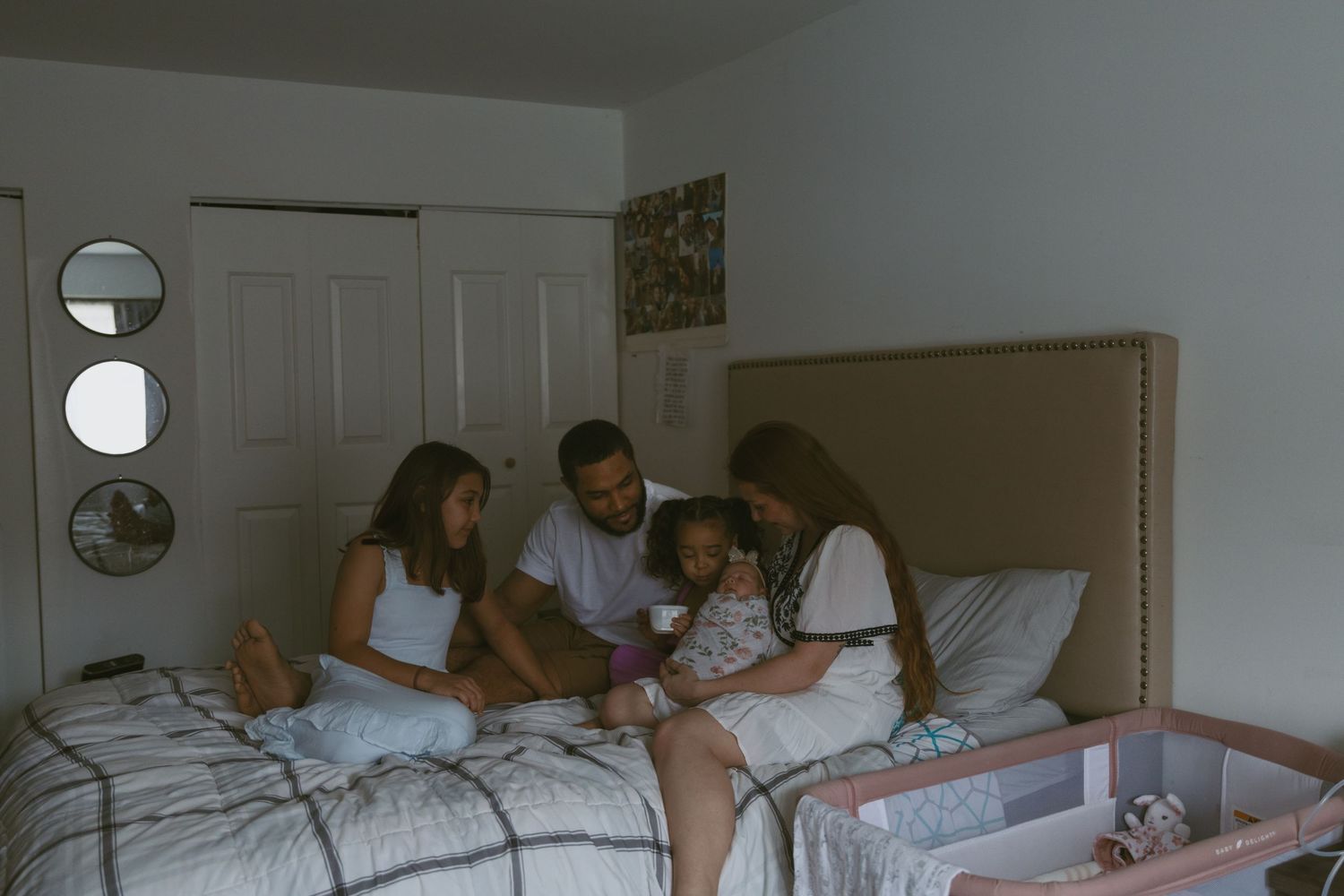 The in-between and slow moments of a family looking mom holding her newborn on the bed during a in-home photoshoot in Sussex New Jersey