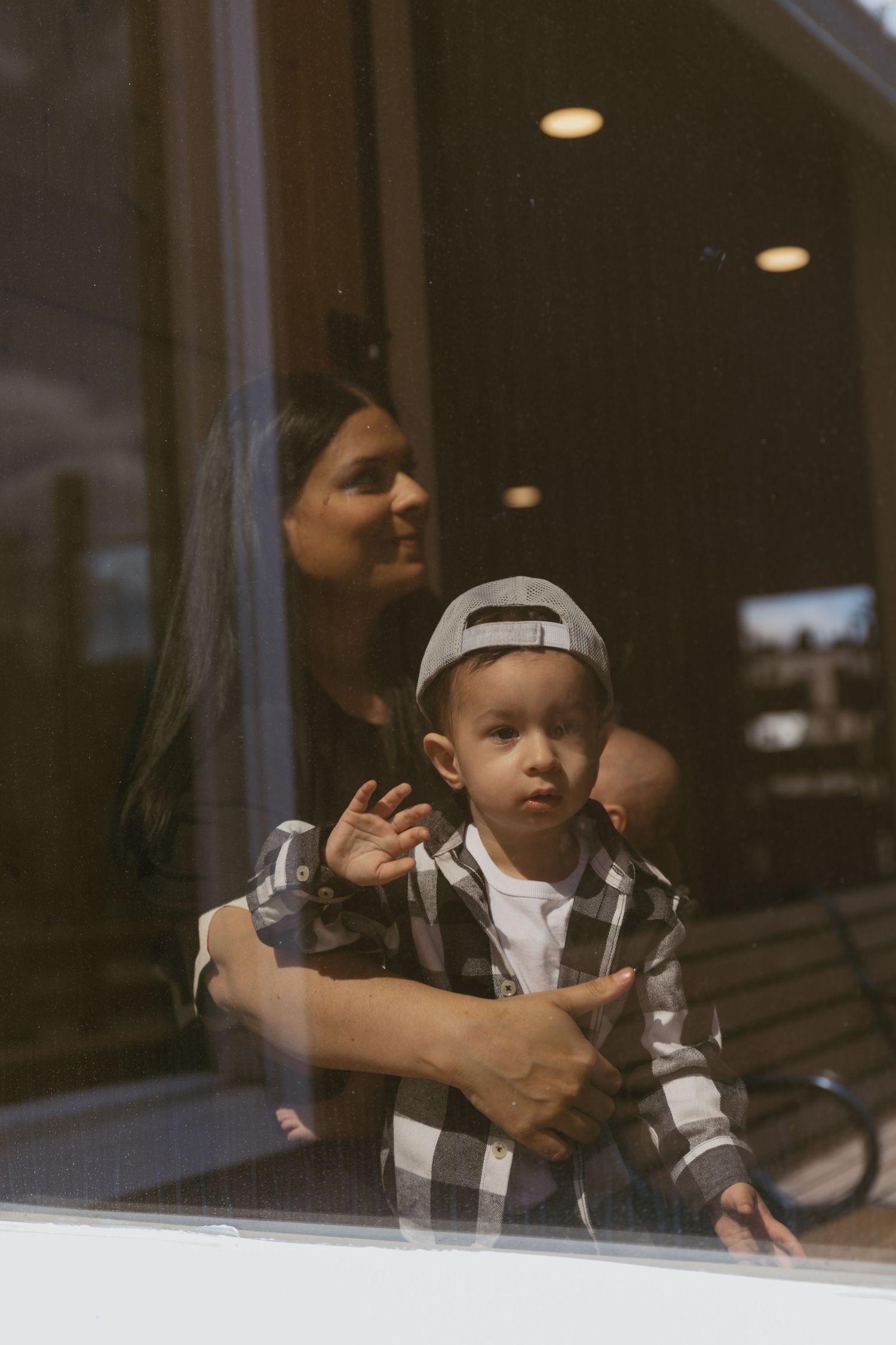 A motherhood lifestyle session. A toddler looking out the window.