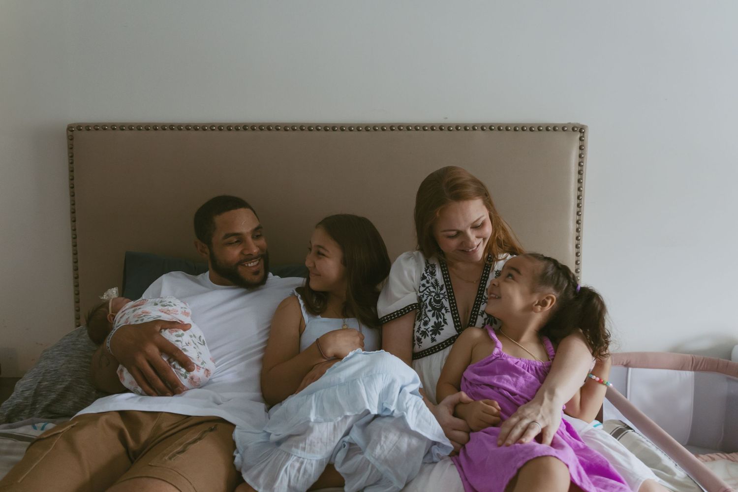 A family snuggling on a bed during an in-home newborn photoshoot in Sussex County  New Jersey.