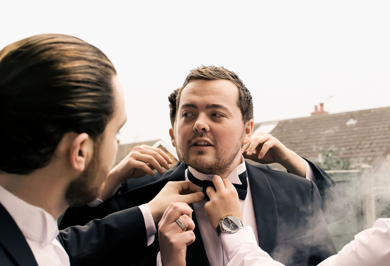 groomsman helping each other get ready for a wedding