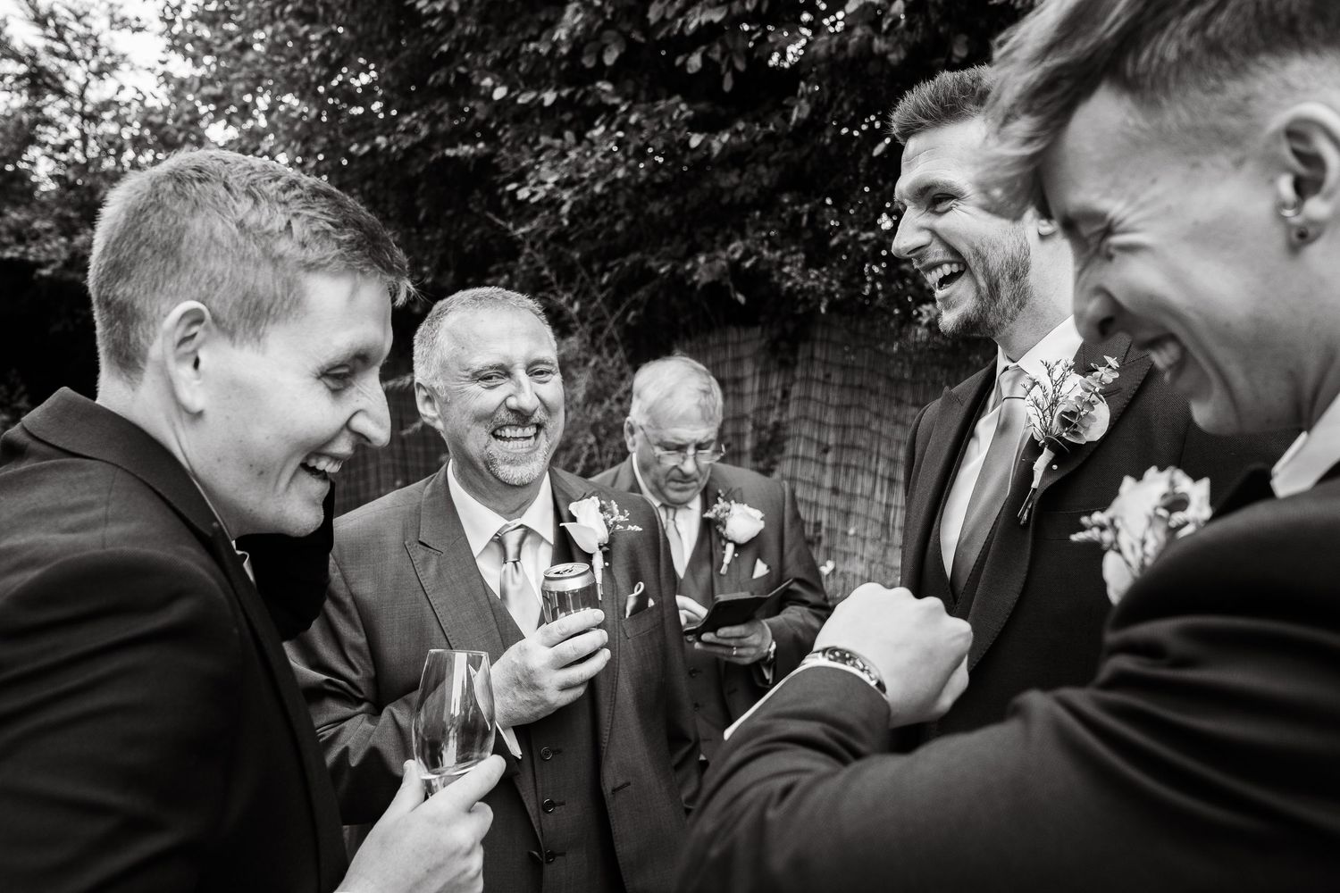 black and white photo of groomsmen laughing at a wedding