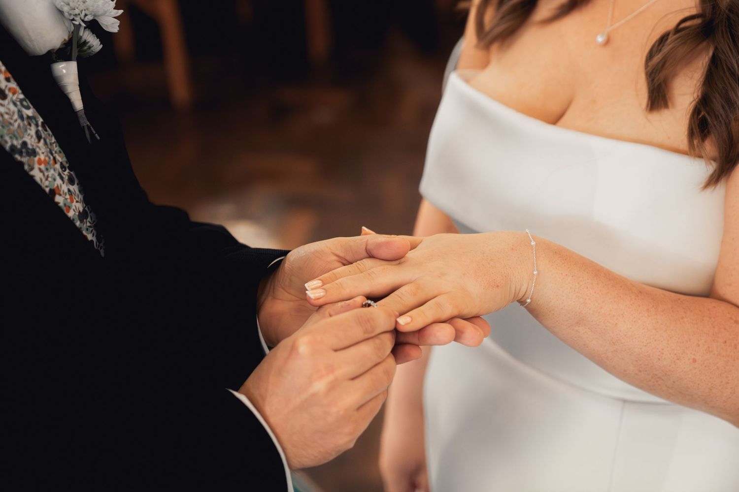 close up photo of a groom putting a ring on his brides finger