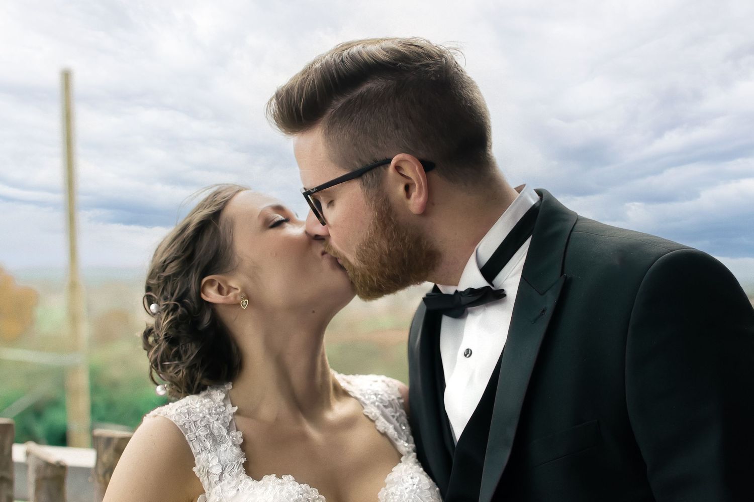 just married couple share a kiss at a zoo in front of a blue sky.