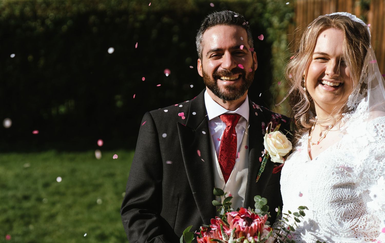 just married couple smiling outside the church under a shower of confetti
