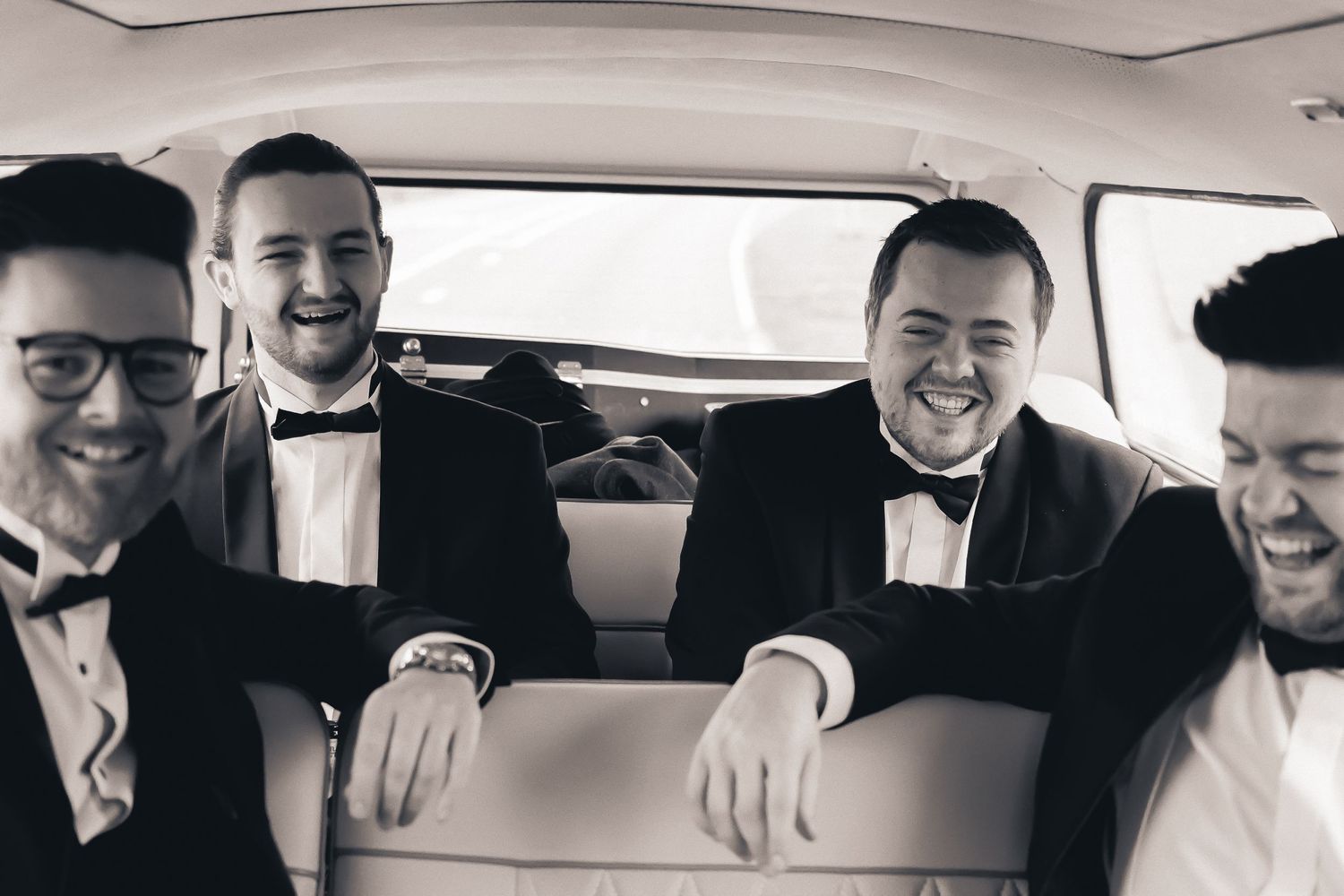 groomsman laughing in the car one the way to the wedding