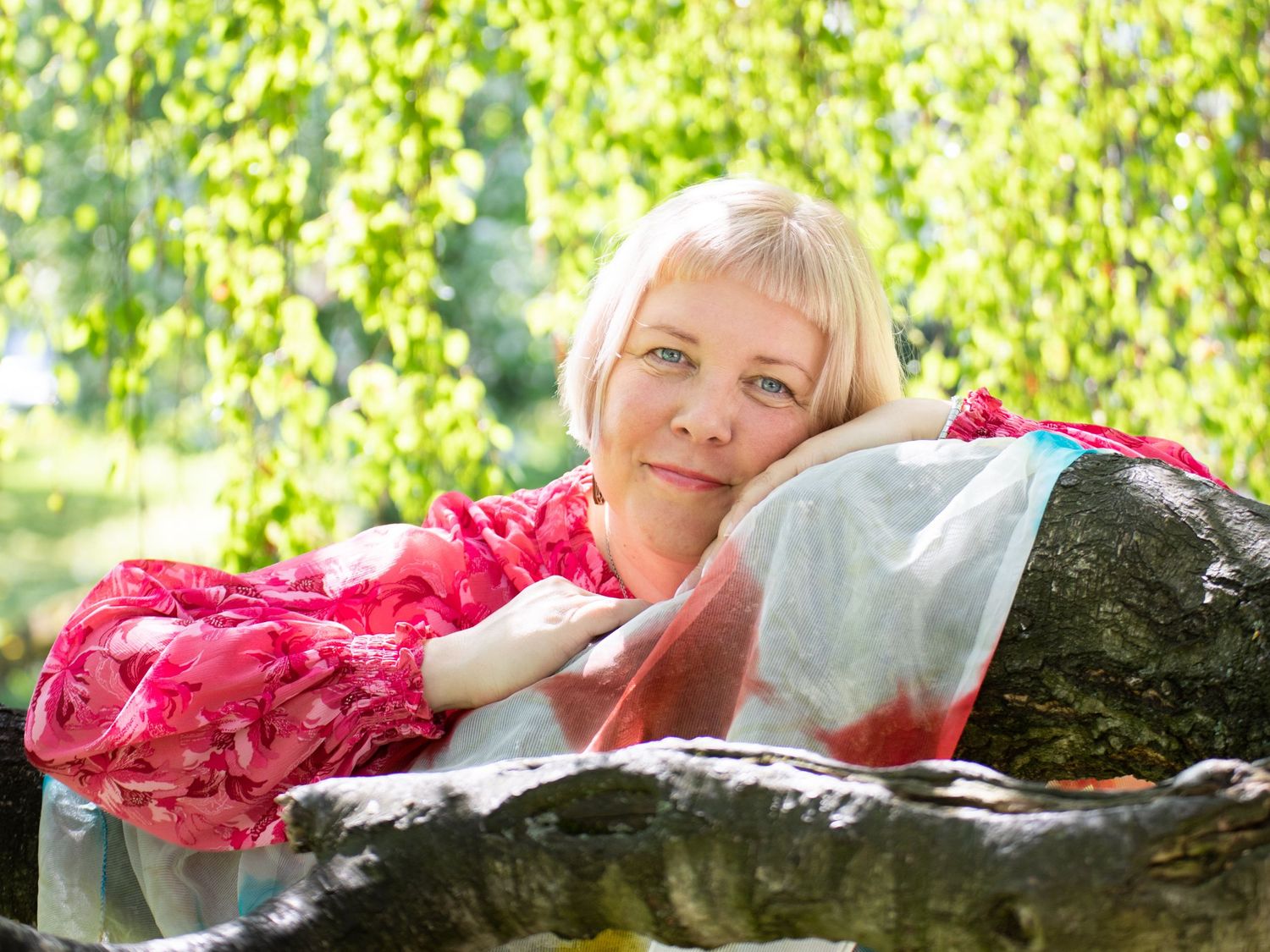Kasvokuva puuhun nojaten ulkona